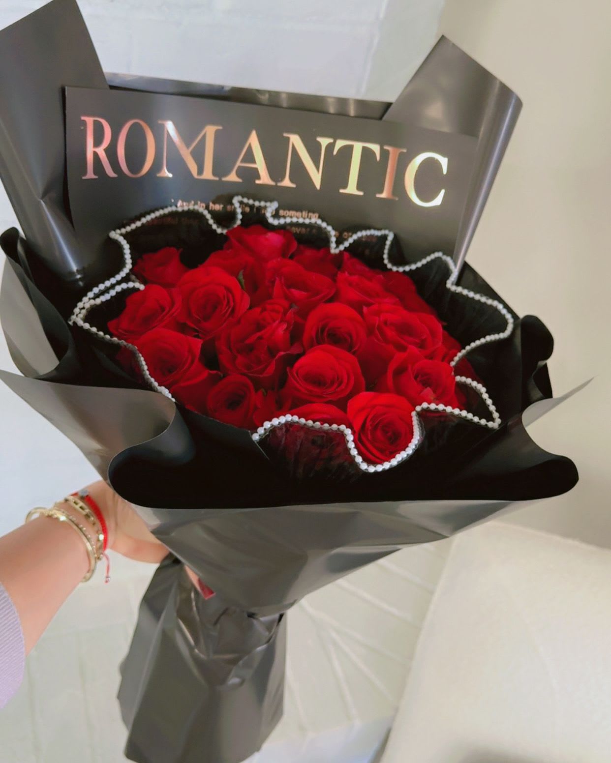 Bouquet of red roses wrapped in black paper with a "ROMANTIC" card