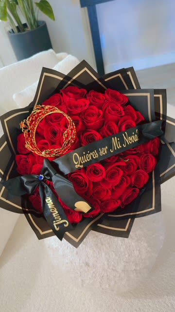 Heart-shaped bouquet of red roses with black wrapping and gold accents