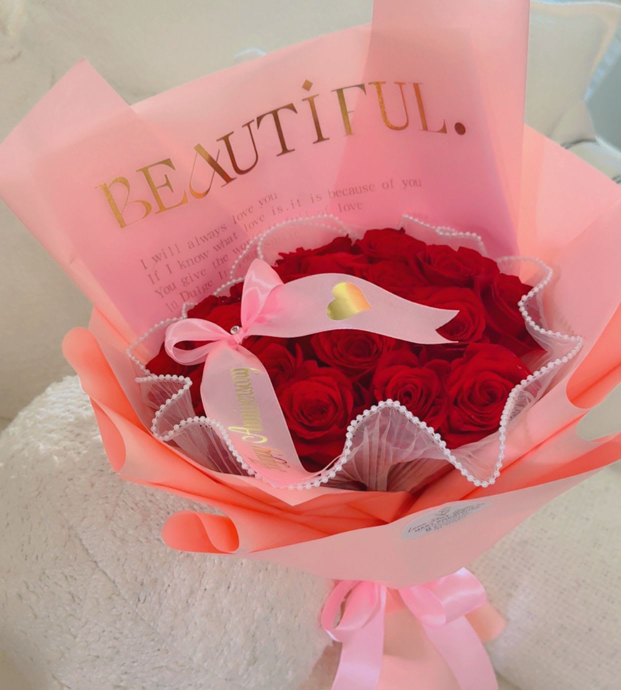 Bouquet of red roses wrapped in pink paper with a ribbon