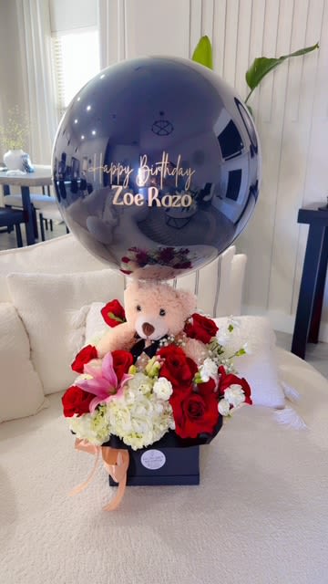 Teddy bear with red and white flowers and a birthday balloon