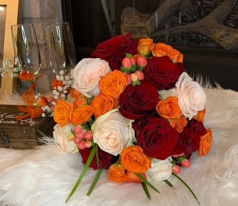 Bouquet of red, orange, and white roses with small berry accents