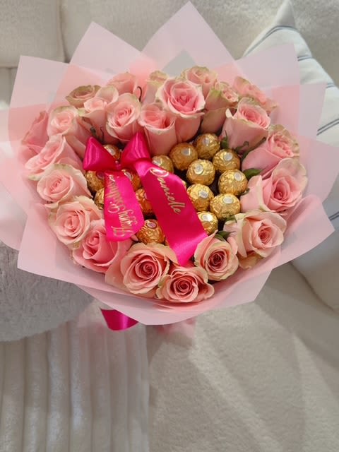 Pink rose bouquet with gold-wrapped chocolates and a satin ribbon
