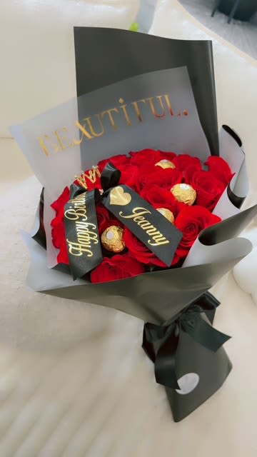 Bouquet of red roses with gold-wrapped chocolates and a black ribbon