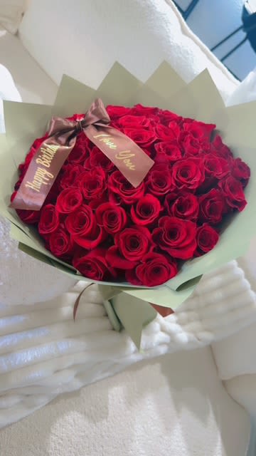 Bouquet of red roses wrapped in pale green paper with a ribbon