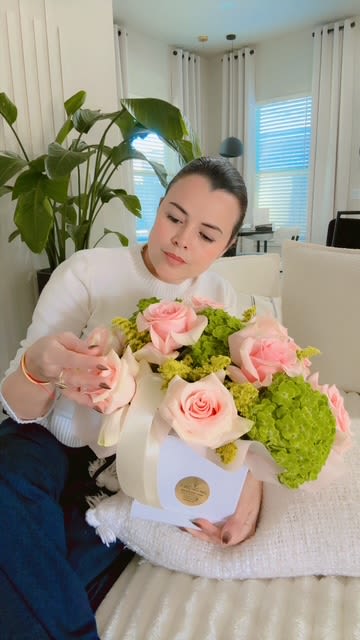 Woman holding a bouquet of pink roses and green hydrangeas in a white box