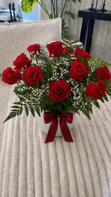 Classic 12  Red Rose vase - A classic and elegant arrangement of a dozen premium red roses in a clean white vase, beautifully finished with a rich burgundy satin bow. Perfect for anniversaries, birthdays, or just because. Flower delivery available in Midland, TX. Un elegante y clásico arreglo de una docena de rosas rojas premium en una base blanca, complementado con un hermoso moño de satén color vino. Ideal para aniversarios, cumpleaños o cualquier ocasión especial. Florería con servicio a domicilio en Midland, Texas.