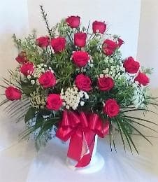 Bouquet of red roses with white filler flowers in a vase, tied with a red ribbon