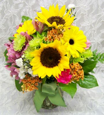 Bouquet of yellow sunflowers and mixed pink flowers in a glass vase