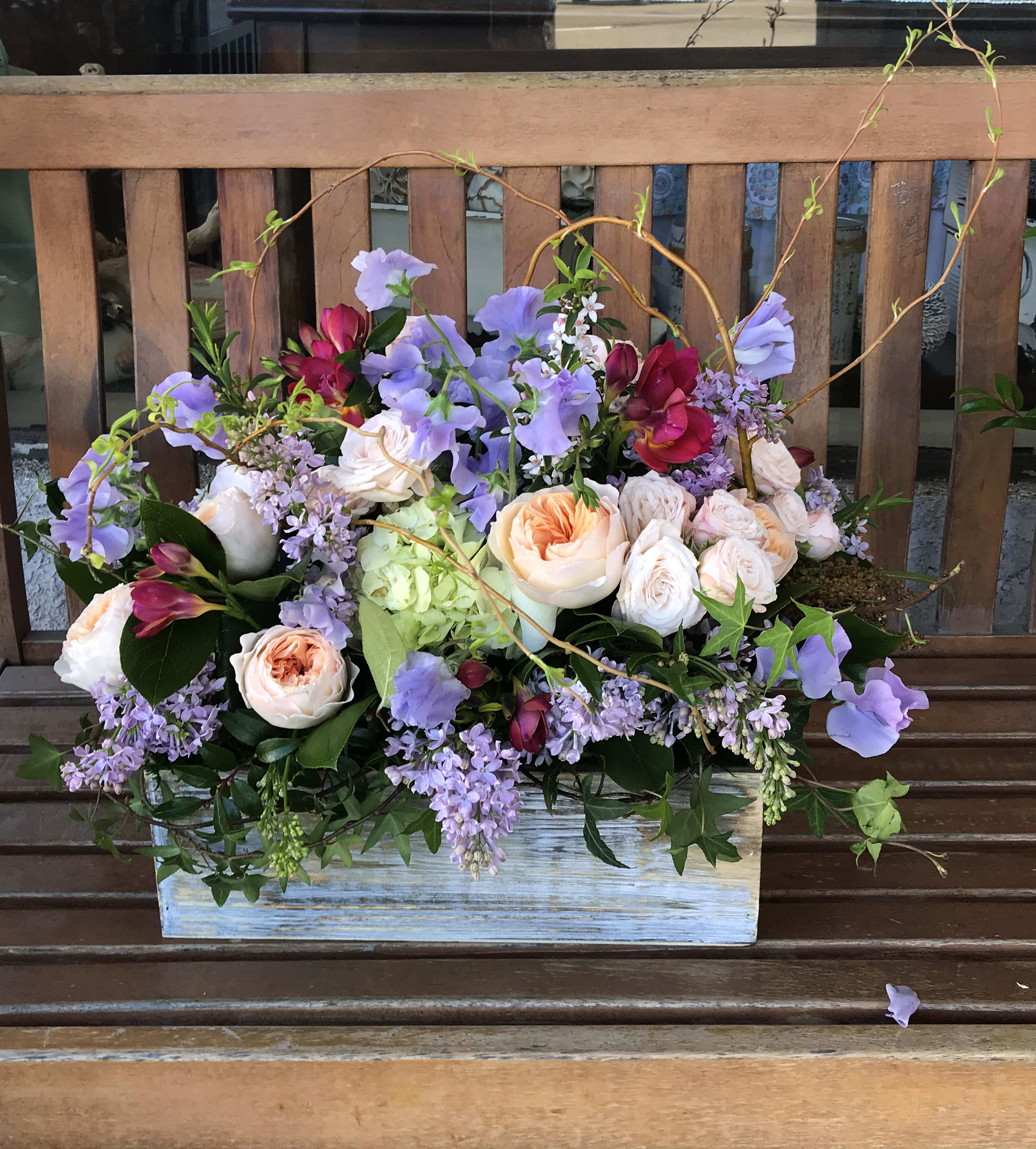 Mixed bouquet of lavender and peach flowers in a rustic wooden box