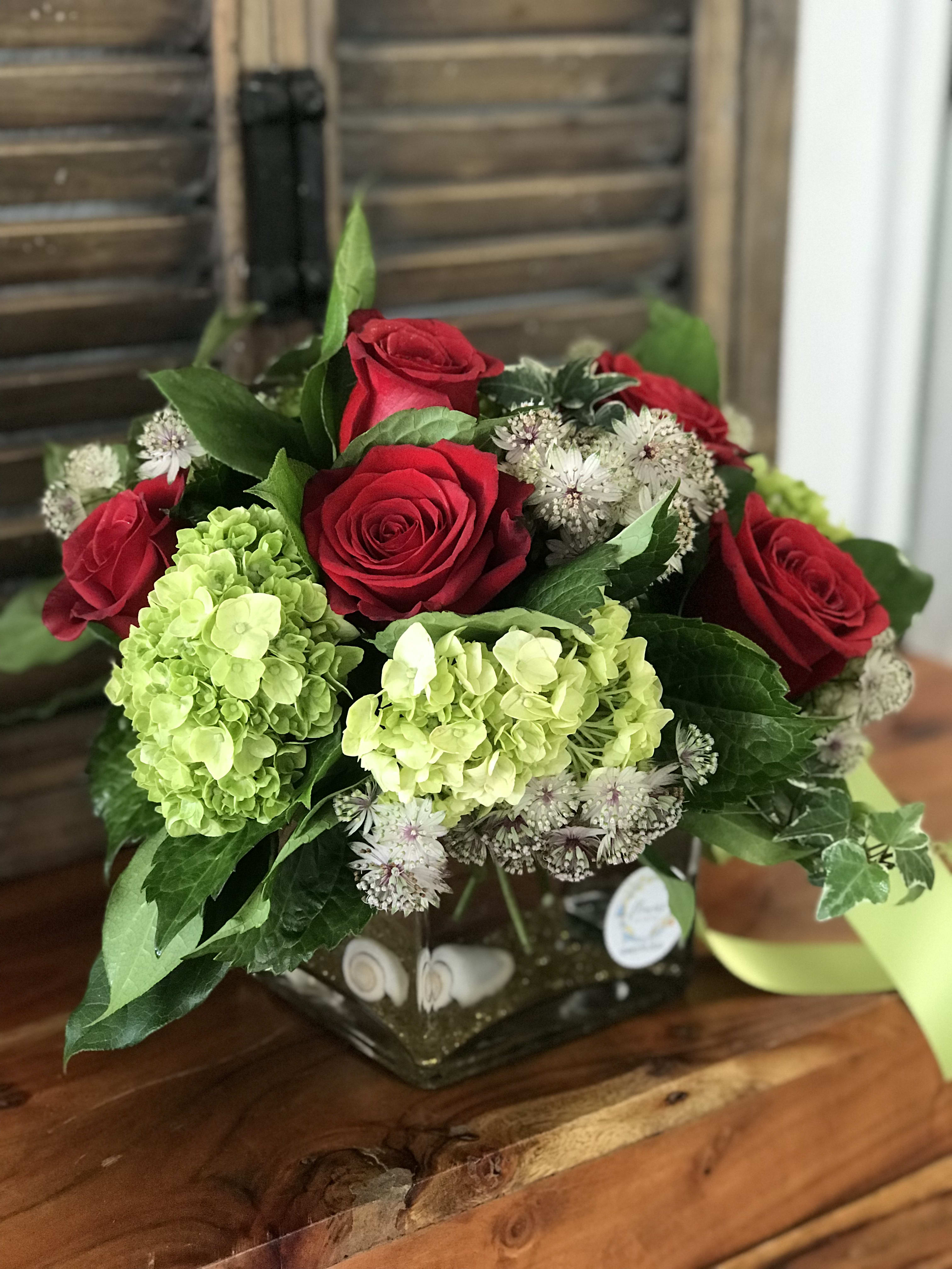 Red roses and green hydrangeas in a square glass vase