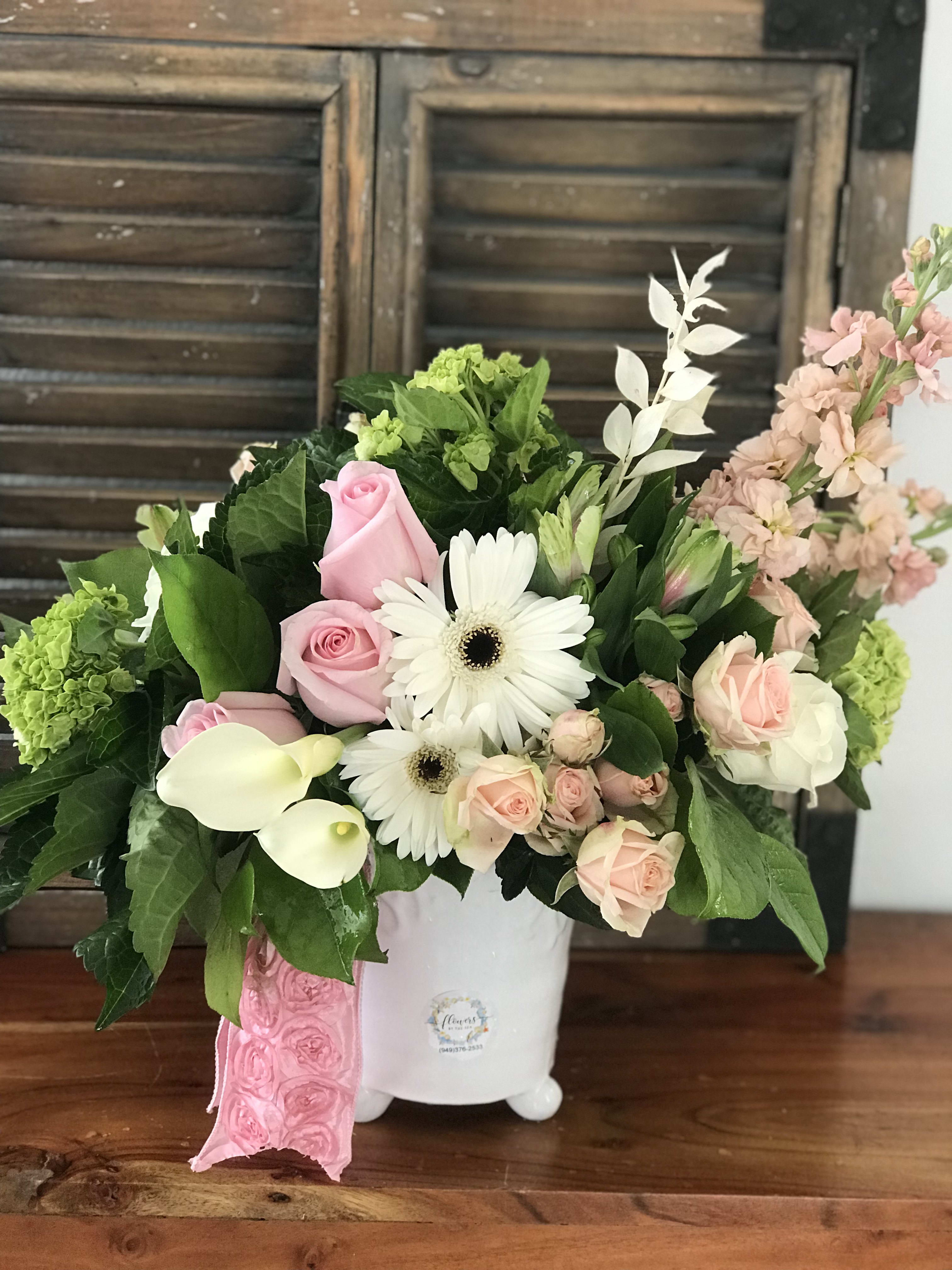 Pink roses and white daisies arranged in a white vase