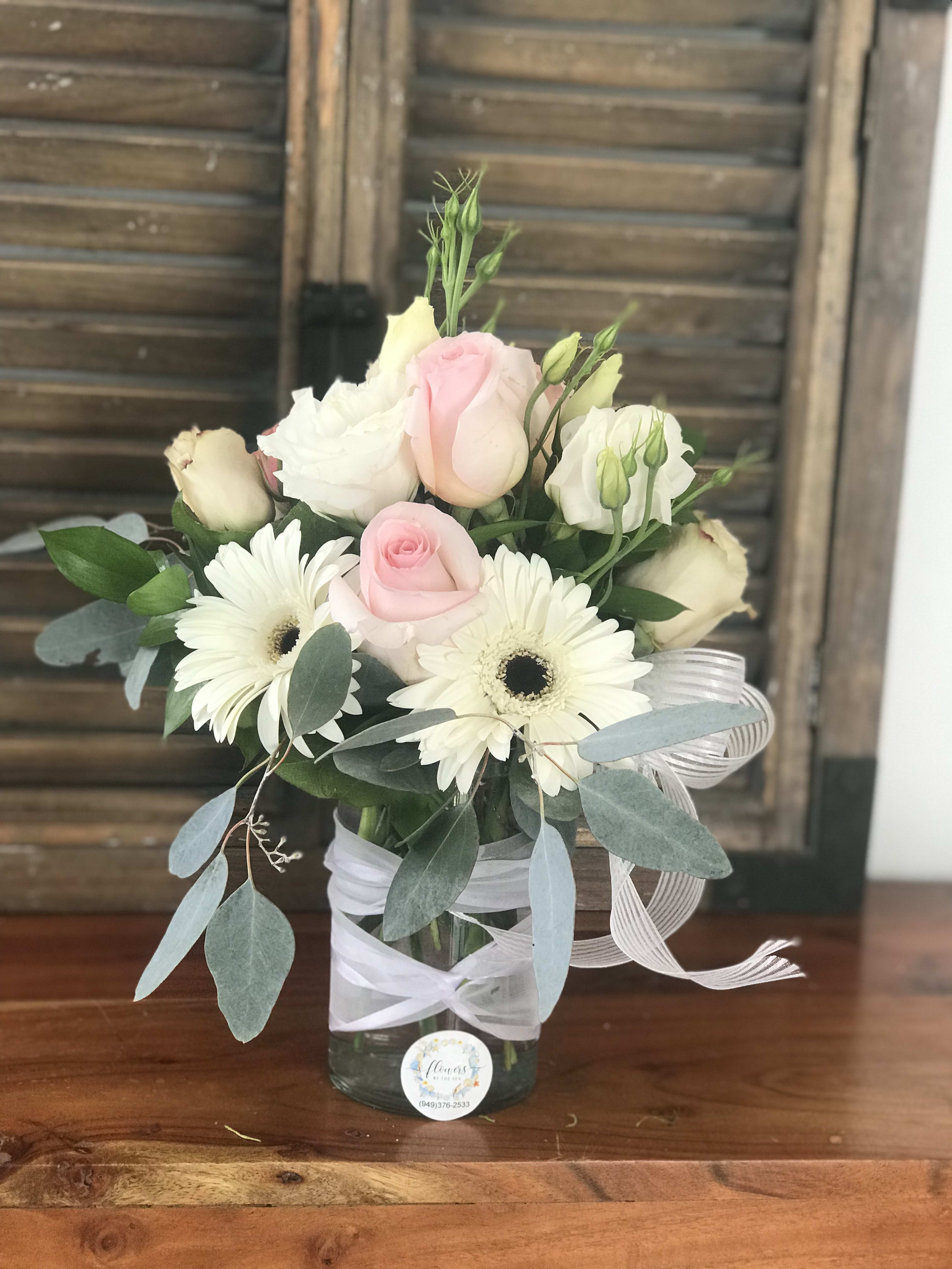 Pink and white roses with white daisies in a glass vase