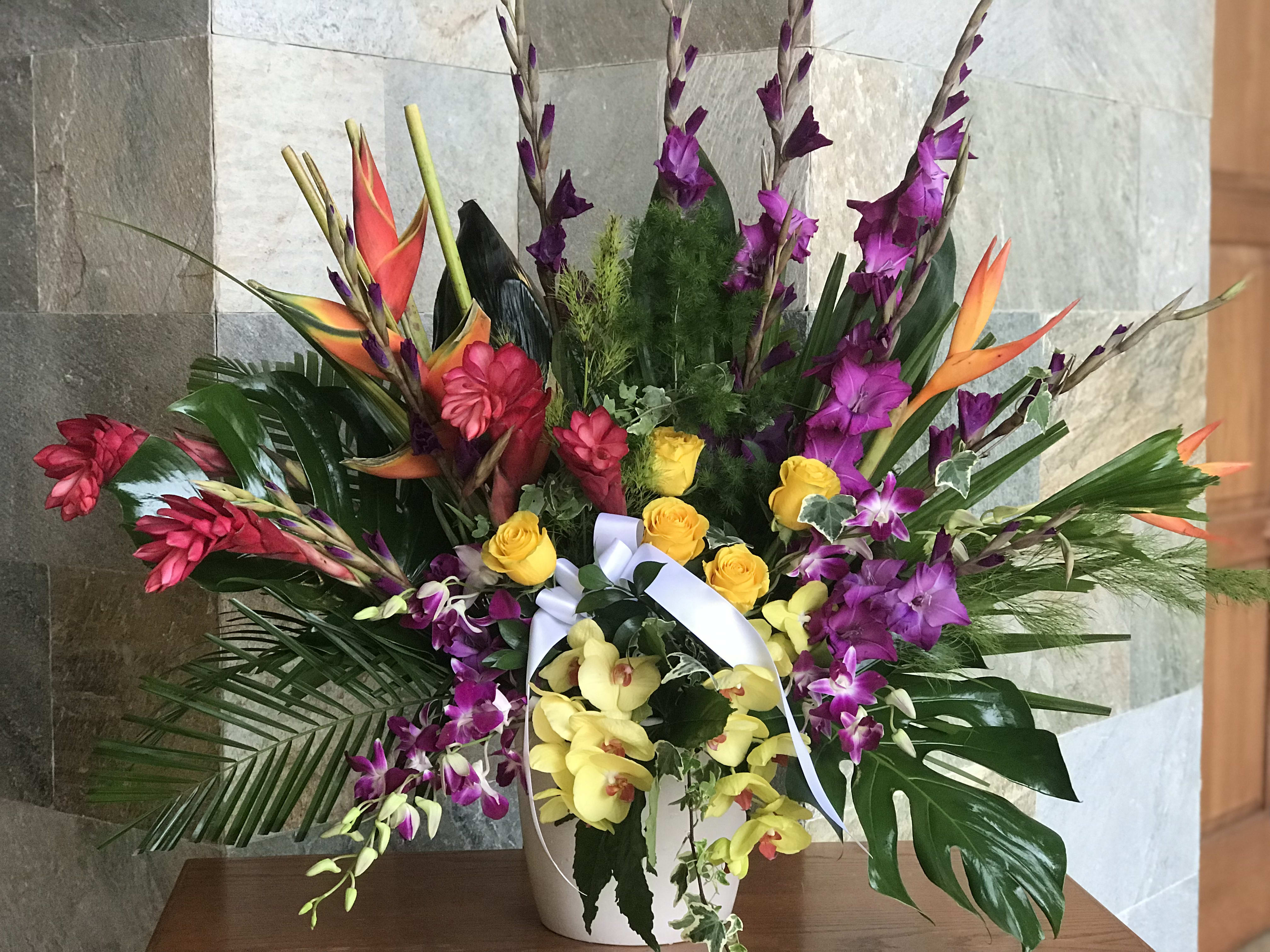 Tropical flower arrangement with orchids and roses in a white vase
