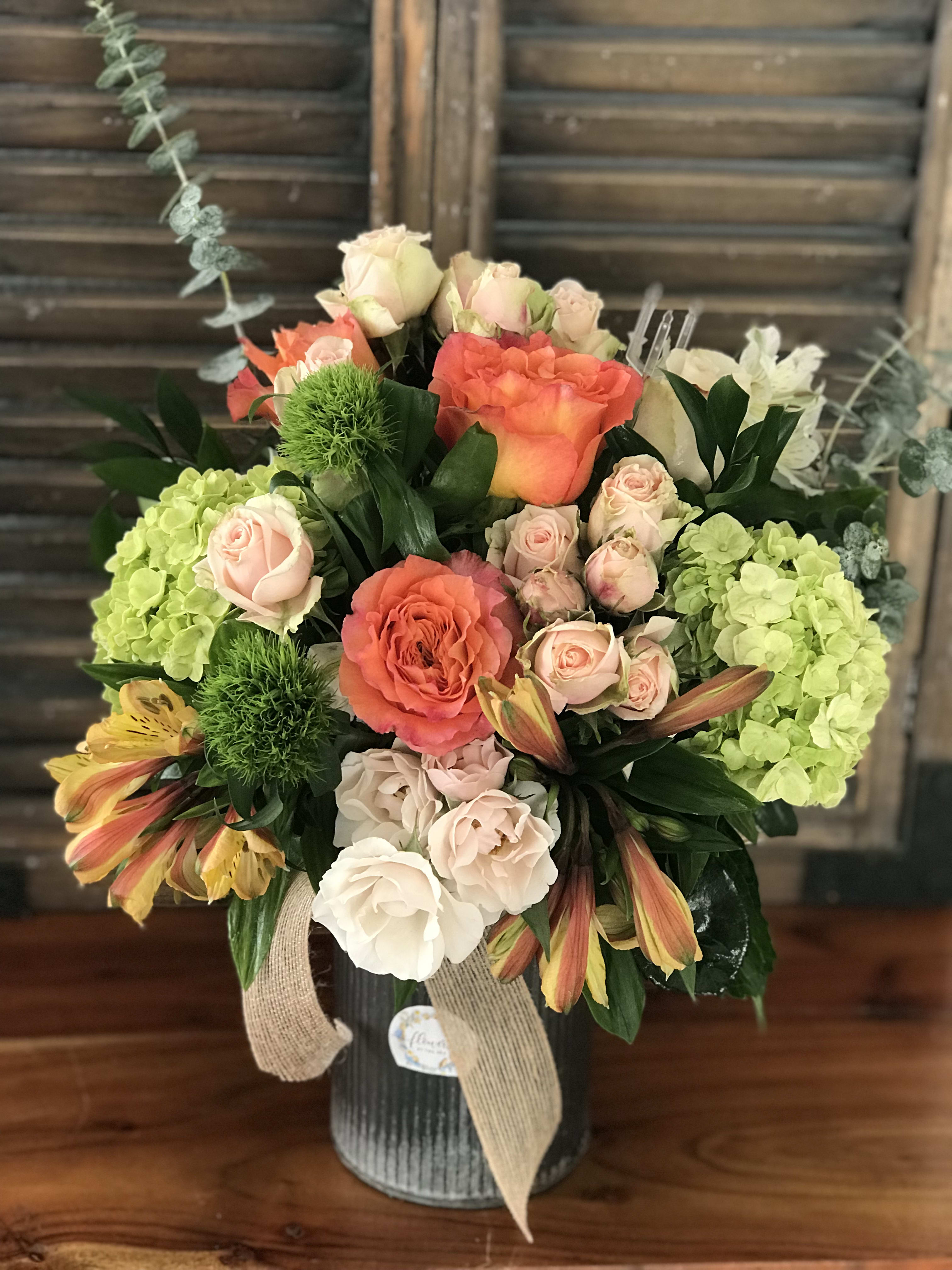 Mixed bouquet in a ribbed vase with coral and blush roses