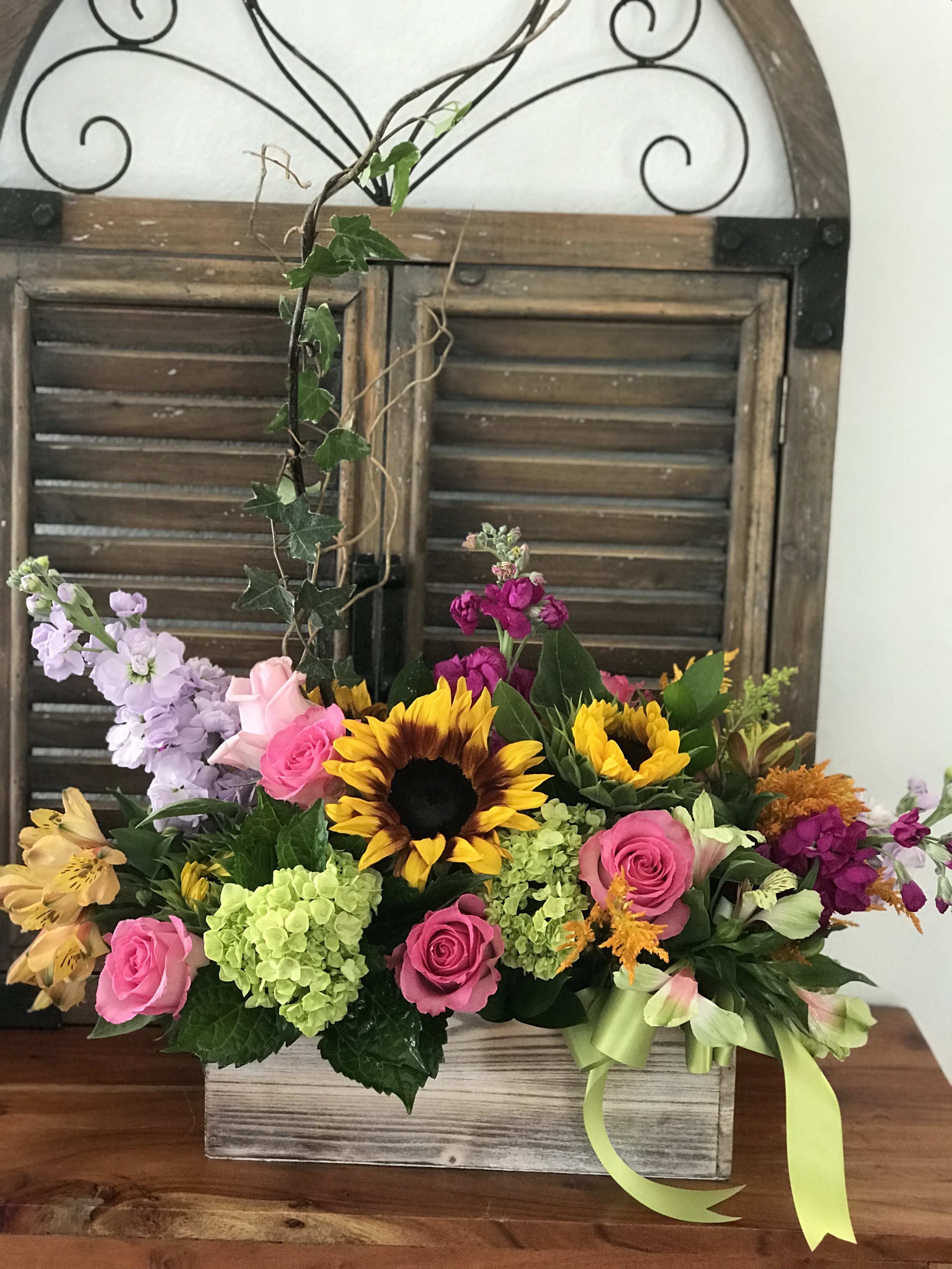 Mixed bouquet with sunflowers, pink roses, and hydrangeas in a wooden box