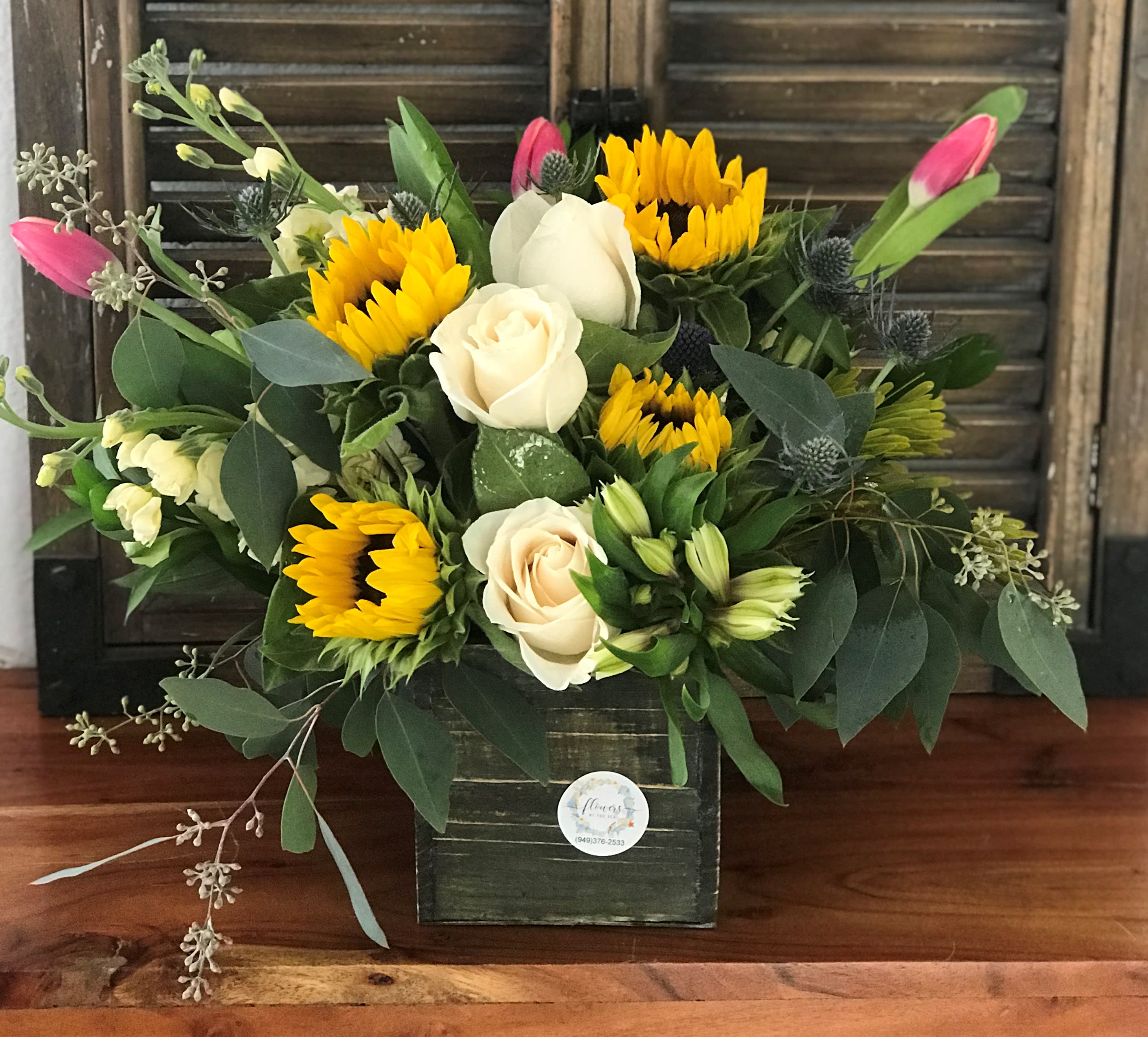 Bouquet of yellow sunflowers and cream roses in a dark box vase
