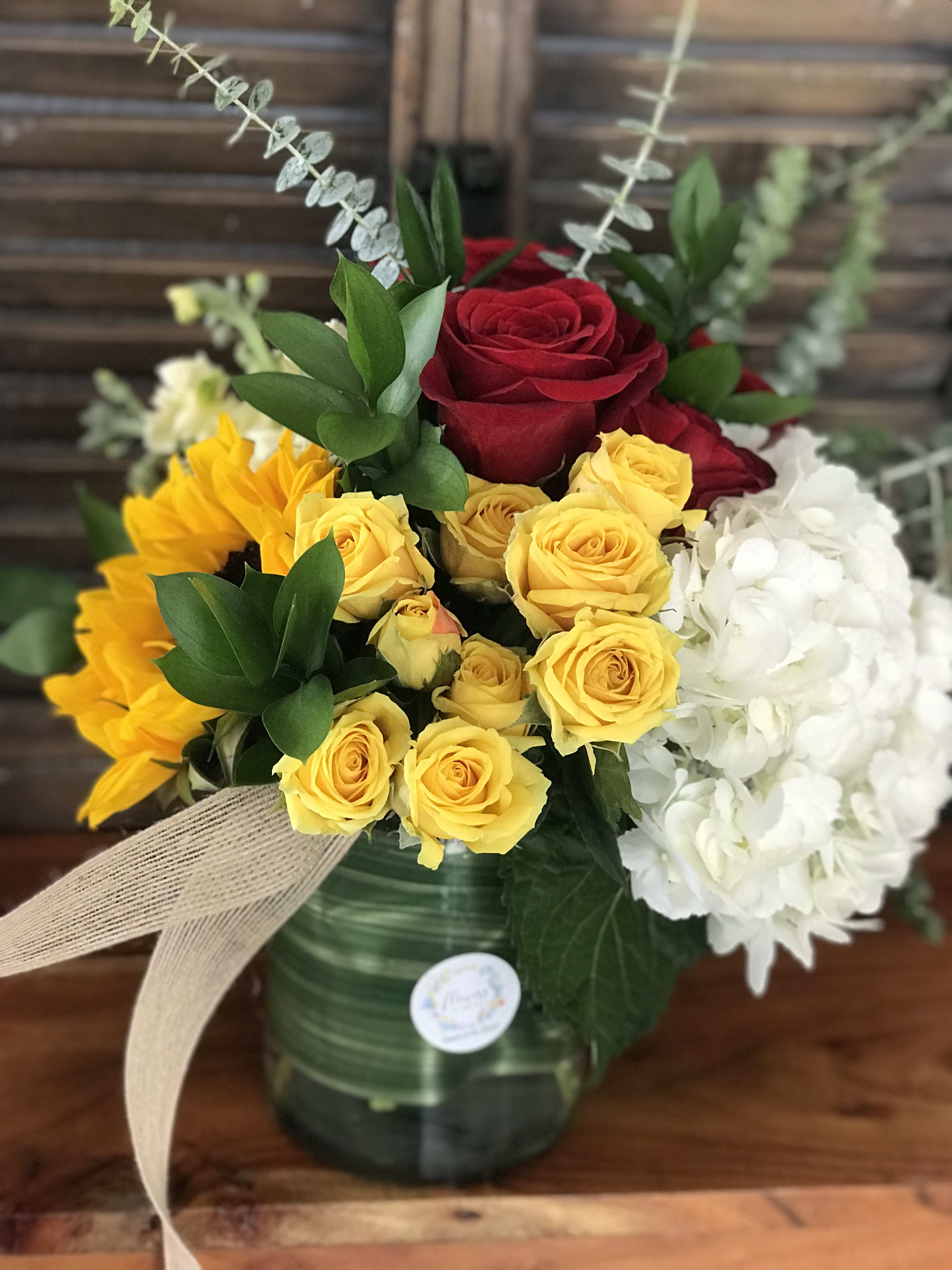 Bouquet of red and yellow roses with white hydrangeas in a glass vase