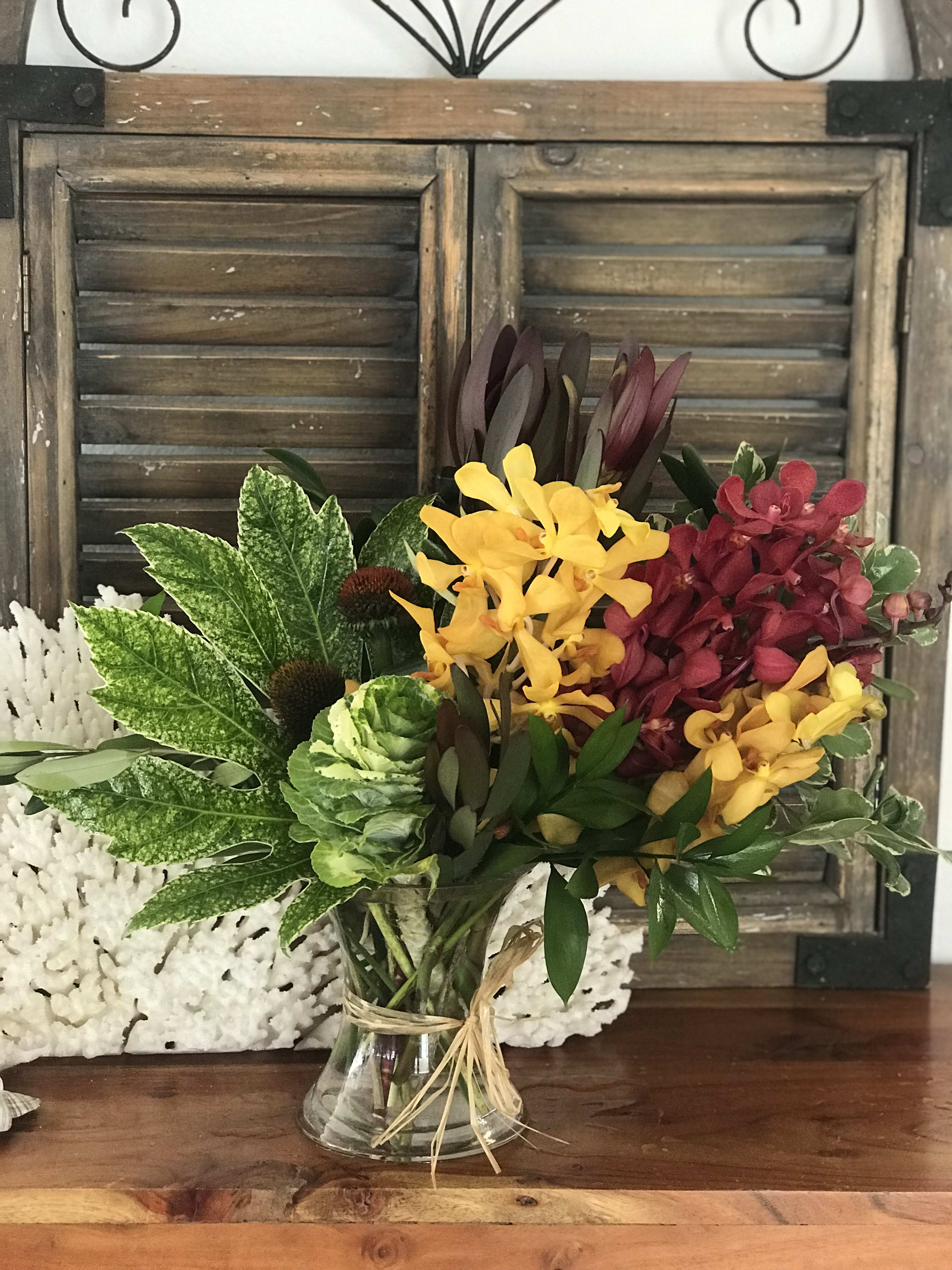 Mixed bouquet of yellow and burgundy orchids in a glass vase