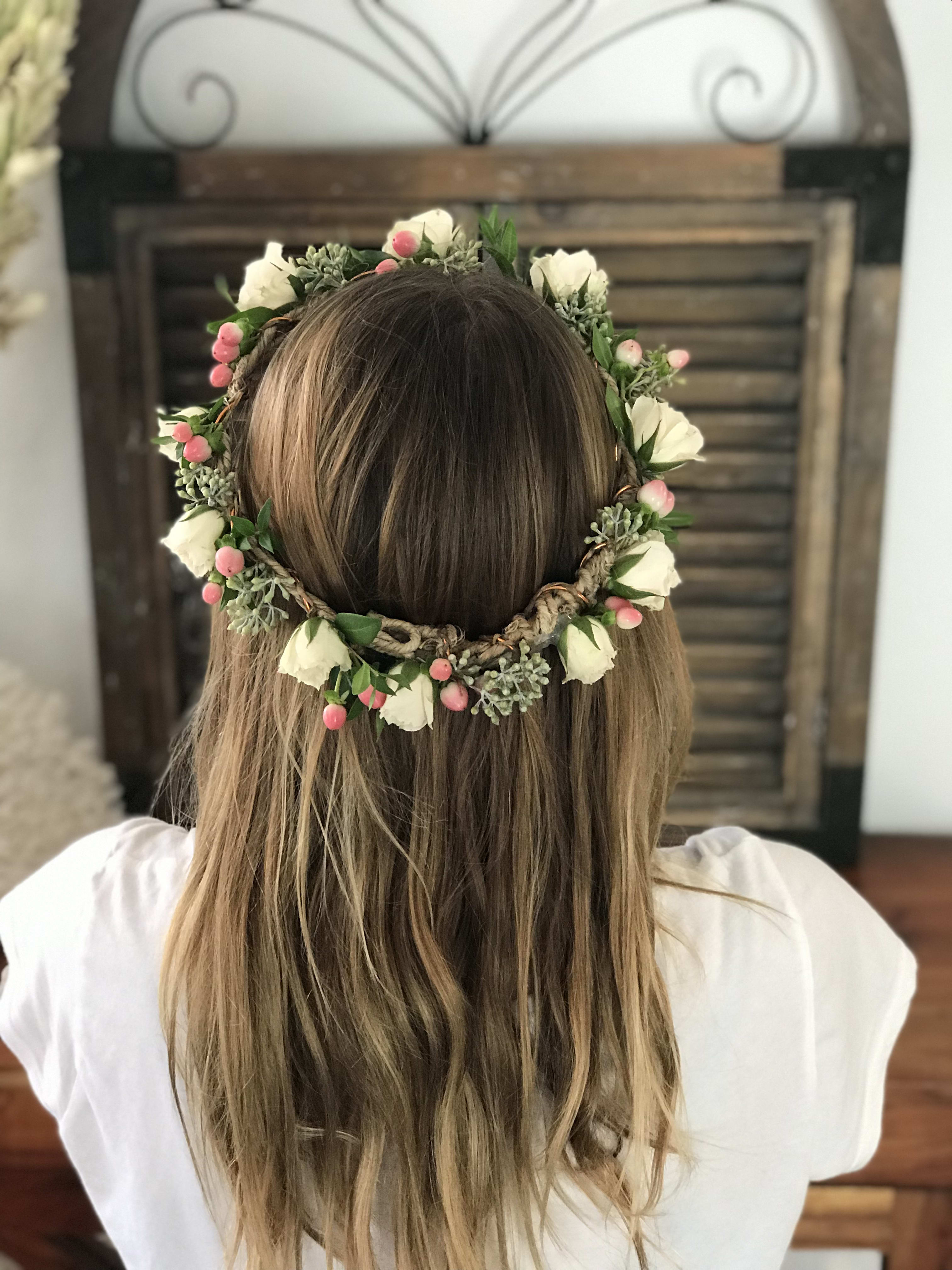 Floral crown with white blooms and pink berries worn on a person's head