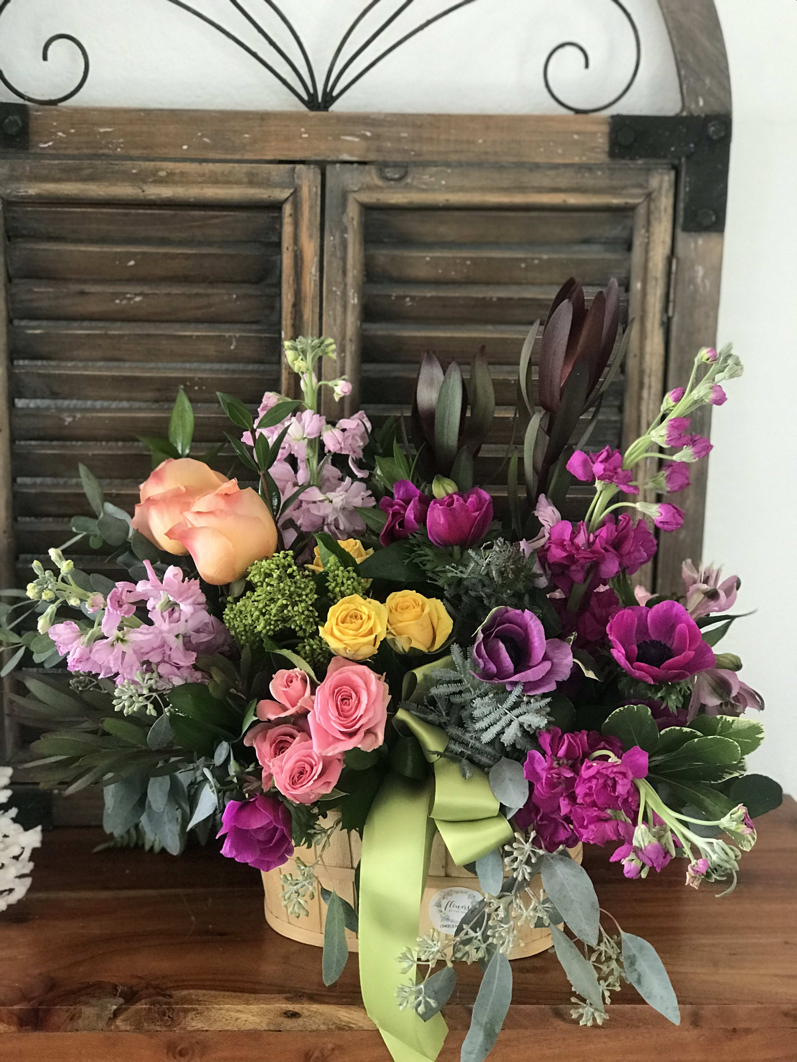 Mixed bouquet in a basket with roses, tulips, and purple blooms