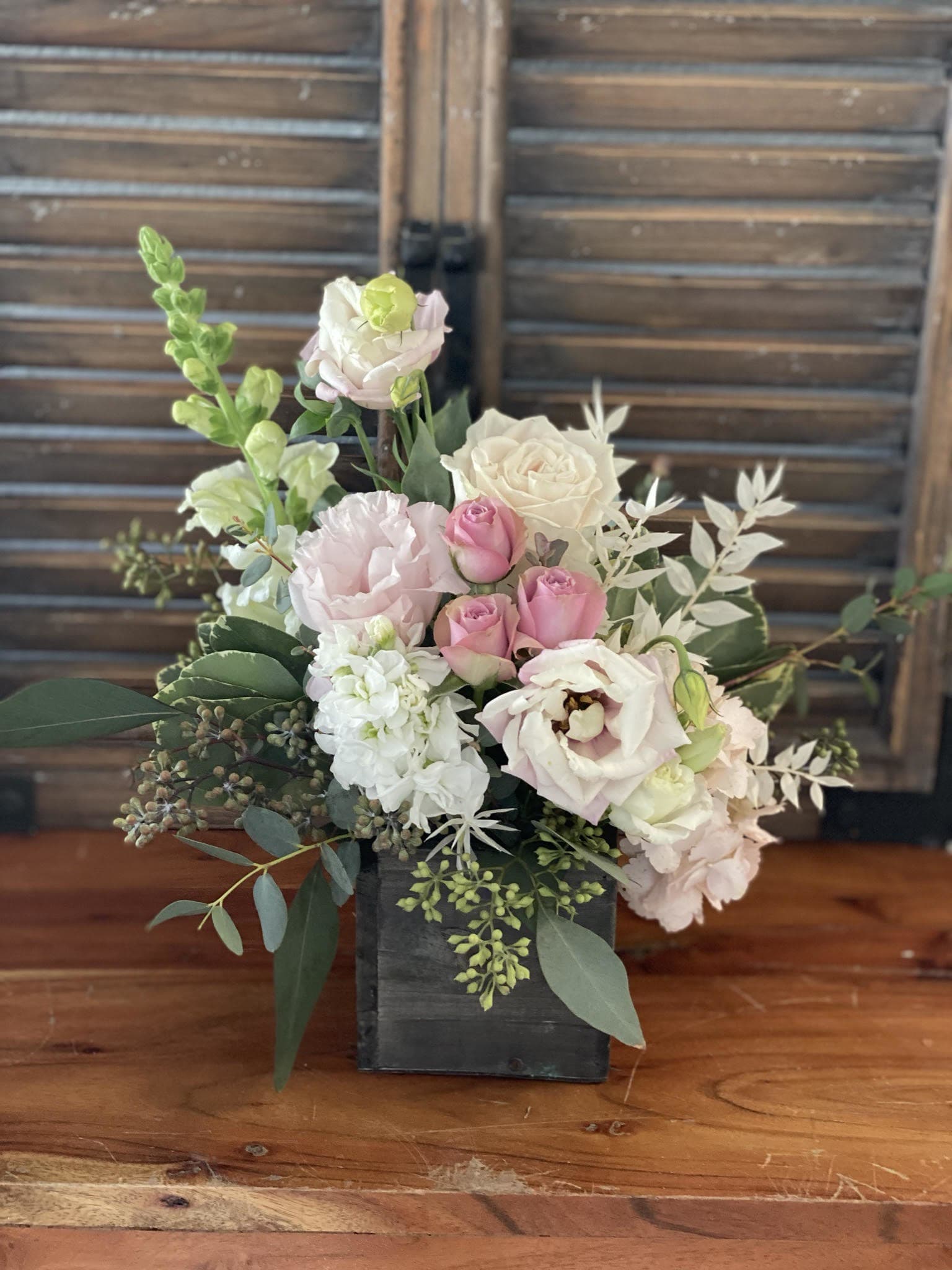Pink and white floral arrangement in a black wooden box