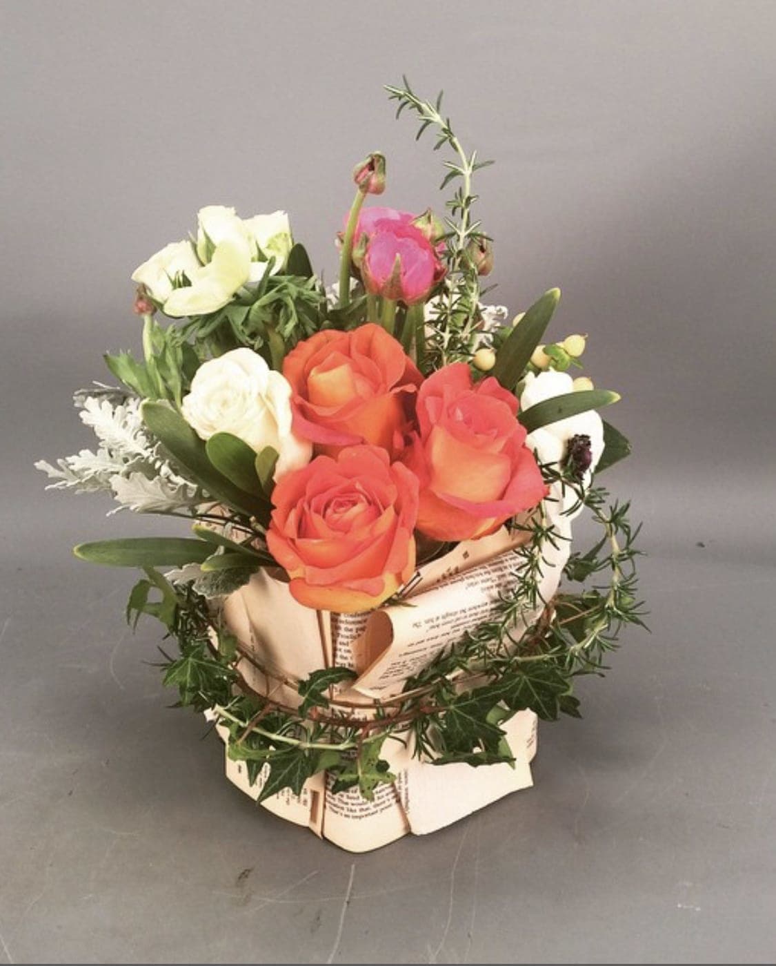 Bouquet of orange and white roses in a paper-wrapped container