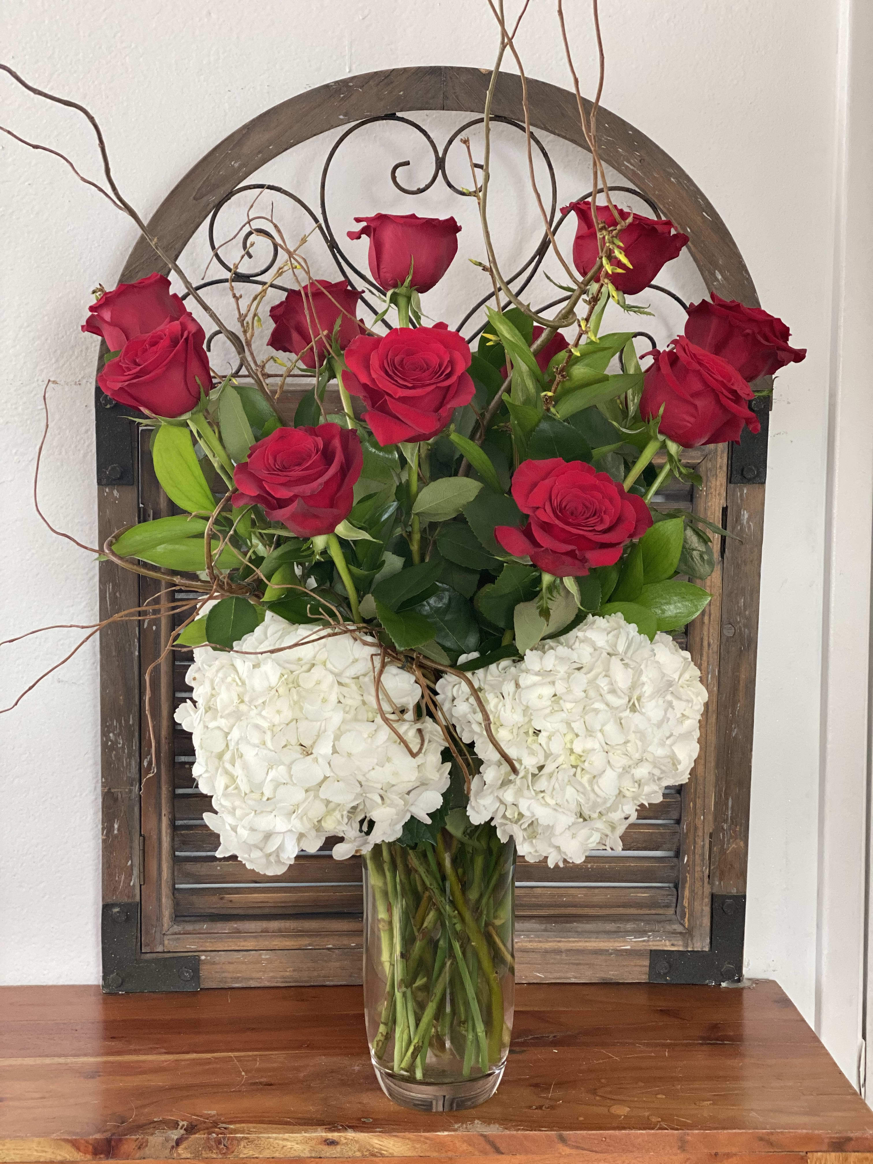 Red roses and white hydrangeas arranged in a clear glass vase