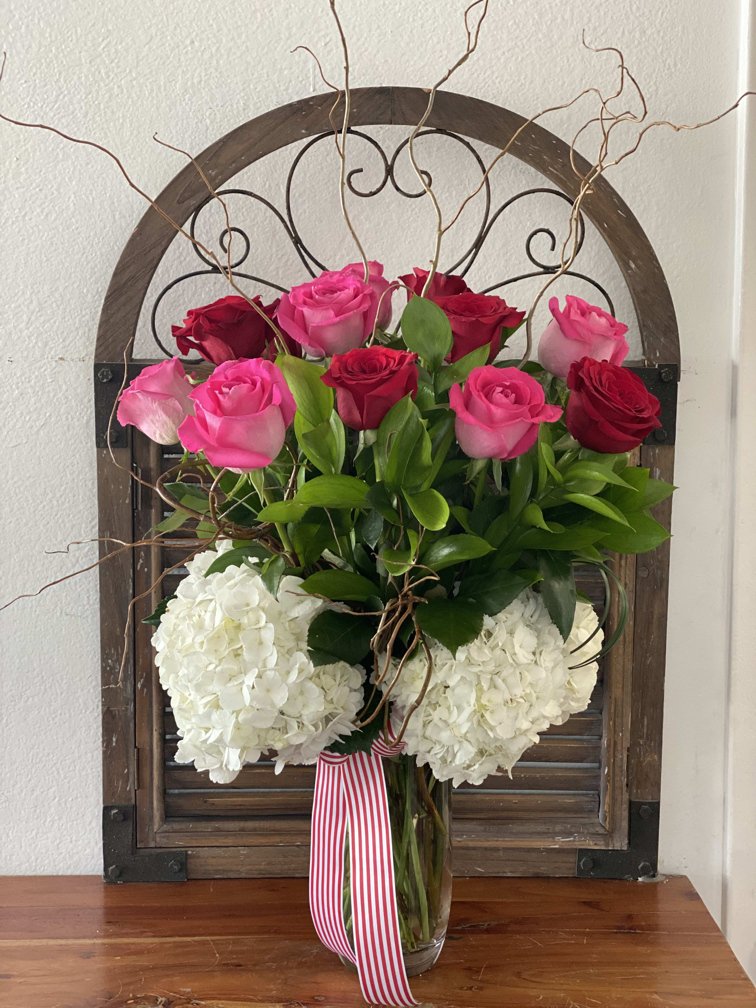 Pink and red roses with white hydrangeas in a glass vase