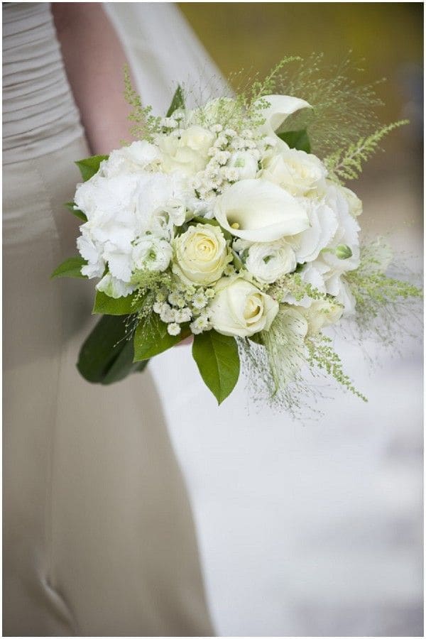 Bridal hand-tied bouquet of white roses, calla lilies, and soft ivory blooms.