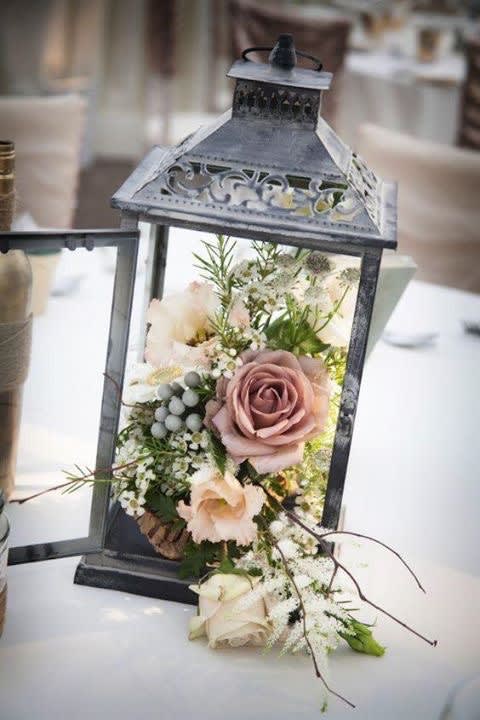 Lantern filled with pale roses and small white flowers