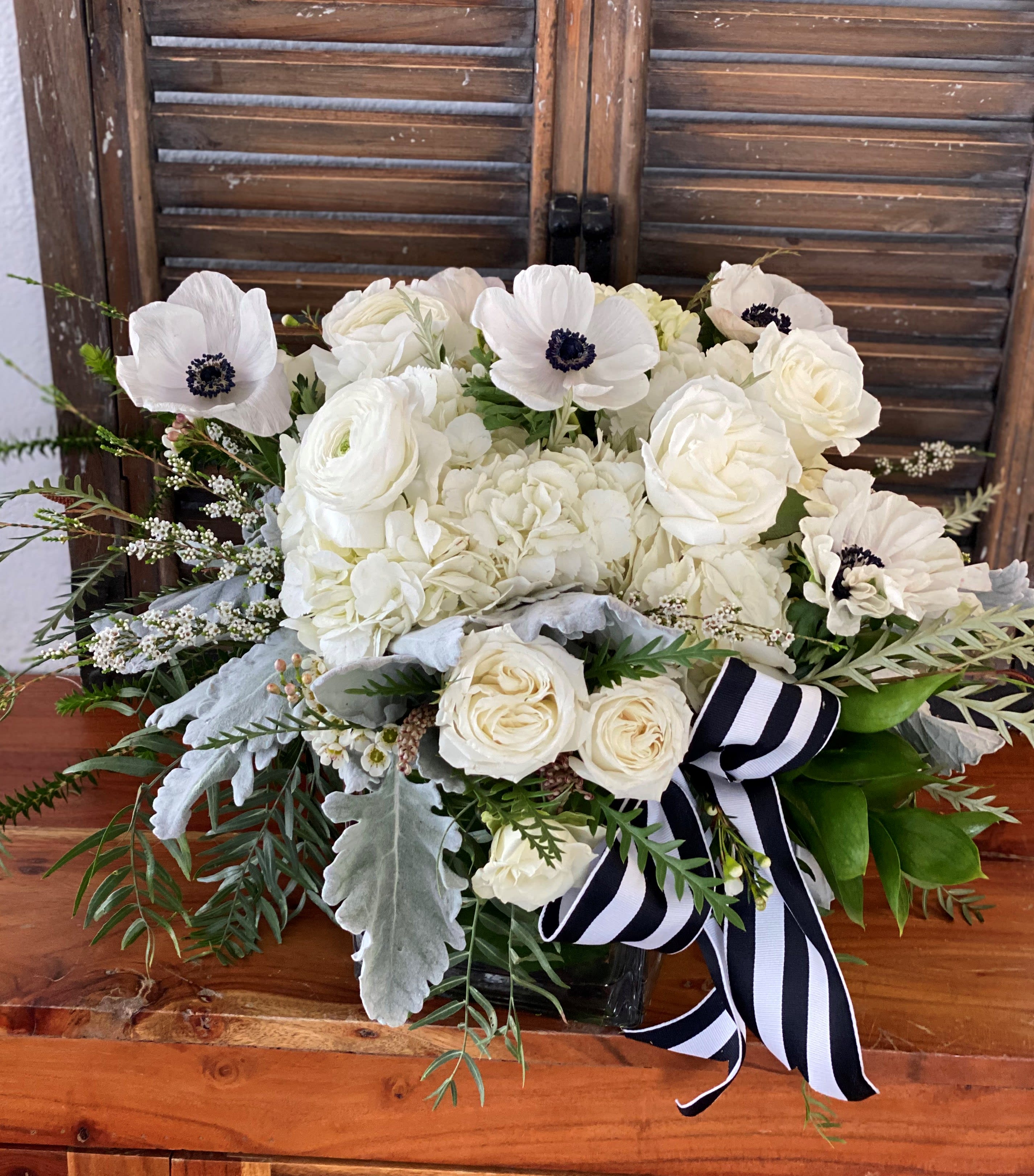 White floral bouquet with a black-and-white striped ribbon