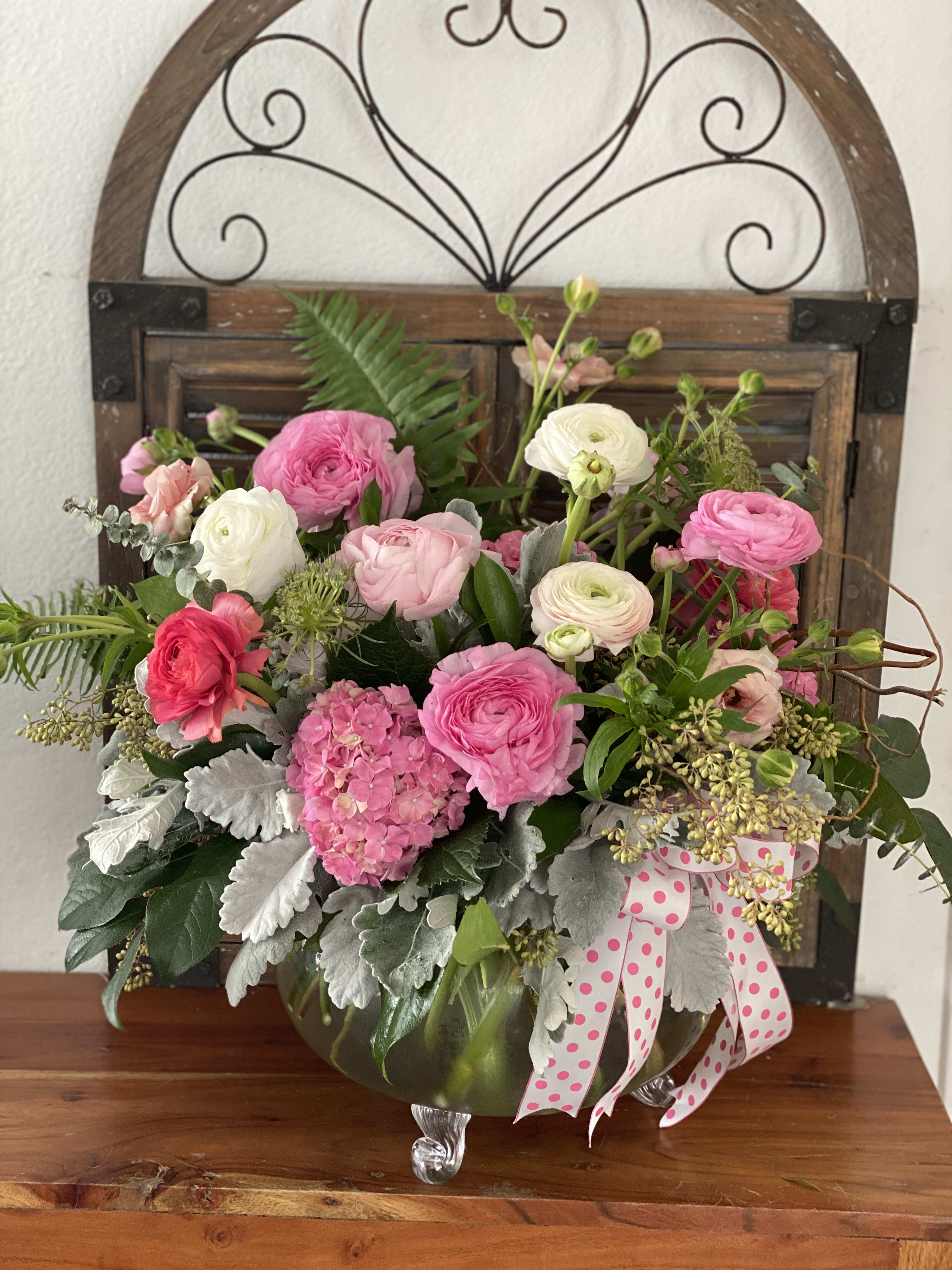 Pink and white flower arrangement in a glass vase with a polka-dot ribbon