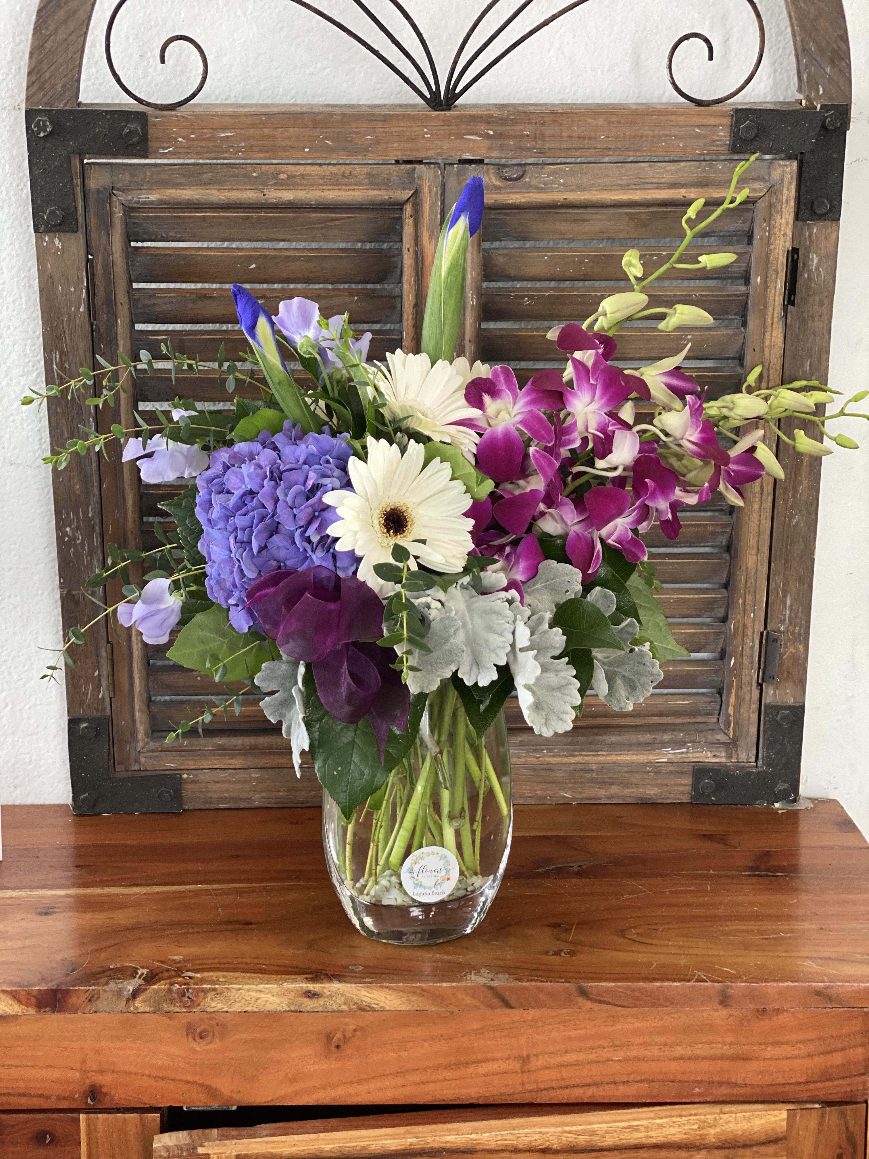 Mixed bouquet in a clear glass vase with purple, white, and pink blooms
