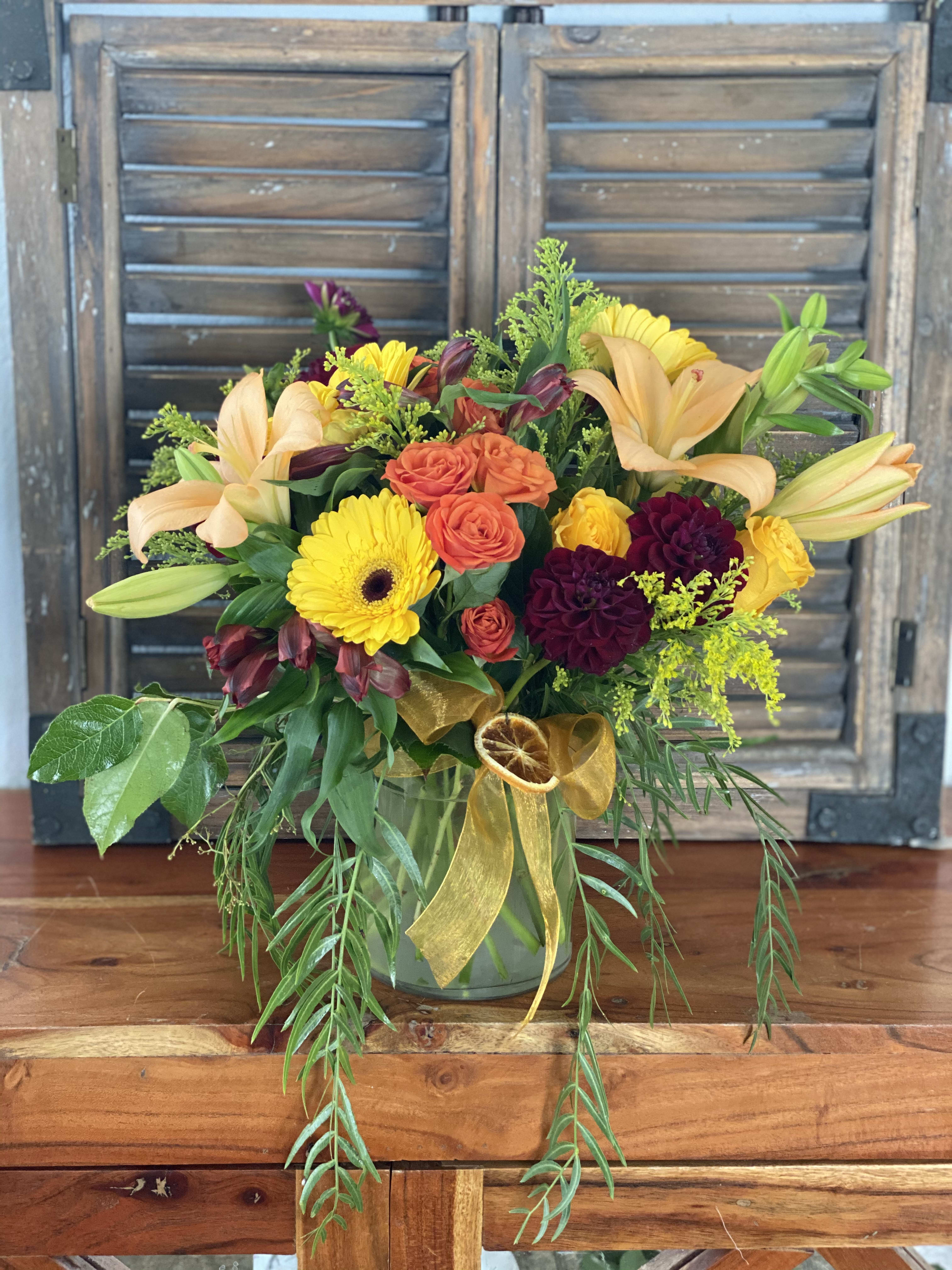 Mixed bouquet in a glass vase with lilies, roses, and yellow daisies