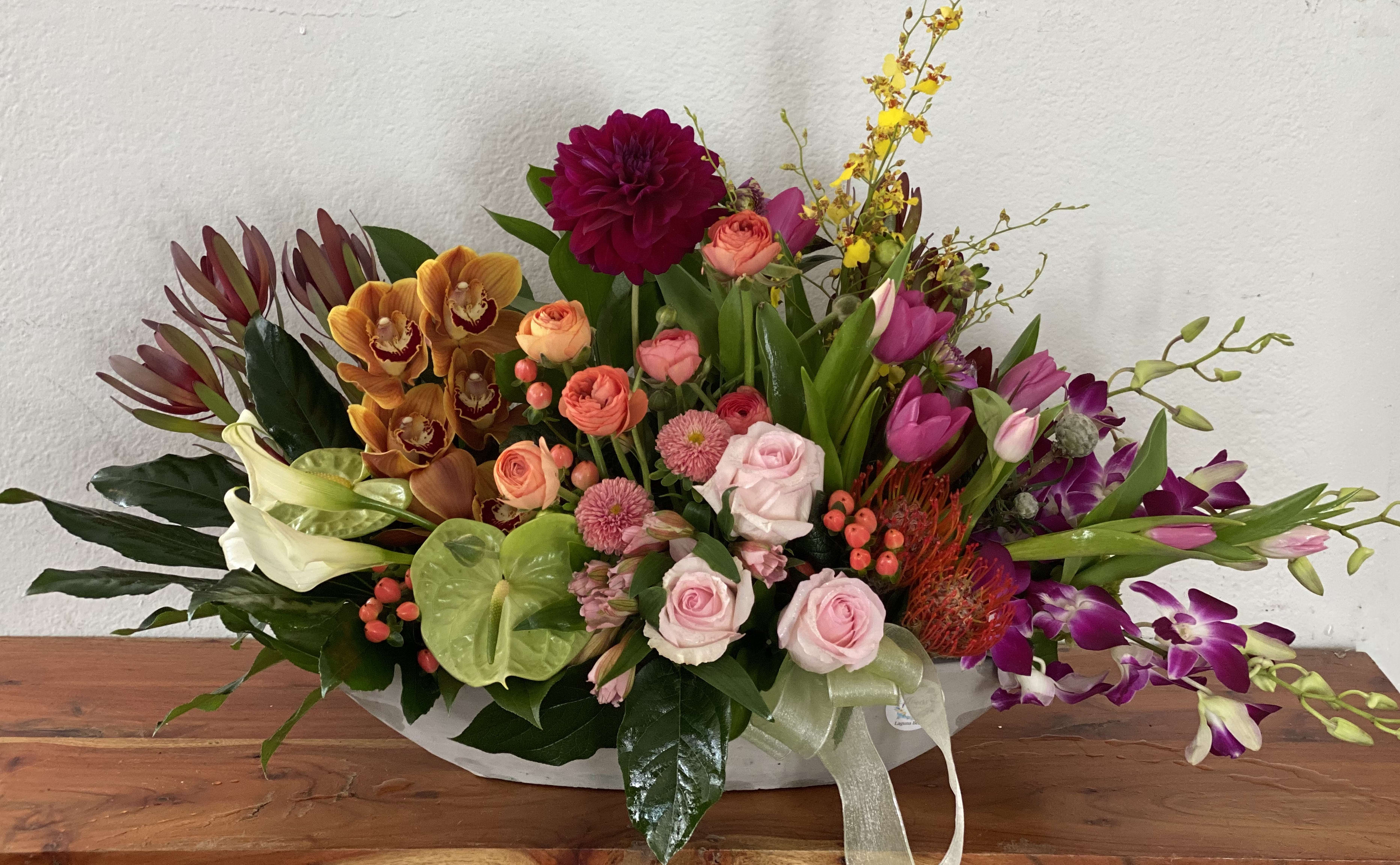 Colorful mixed flower arrangement in a low white container