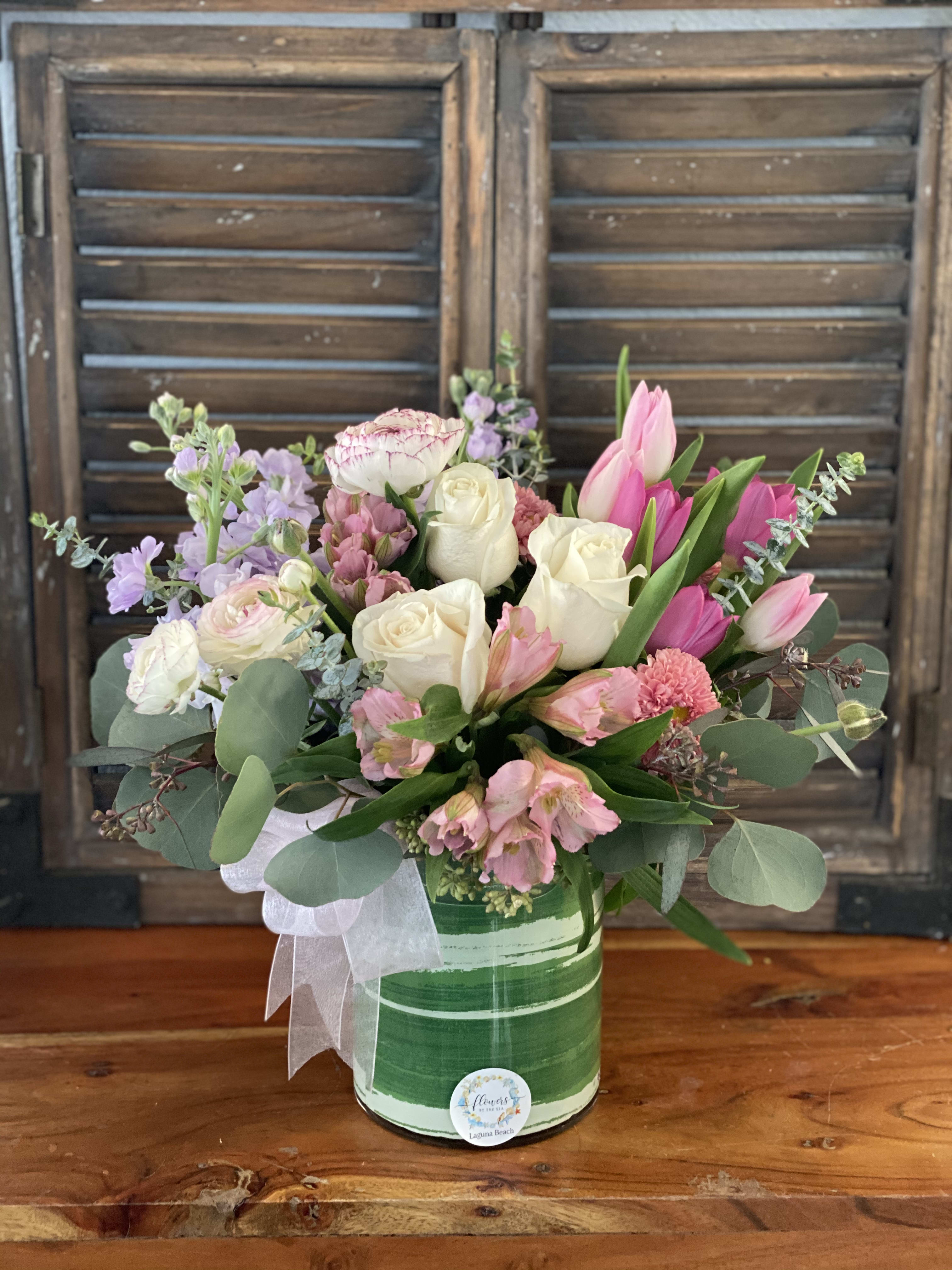 Pink and white mixed flower arrangement in a green striped container