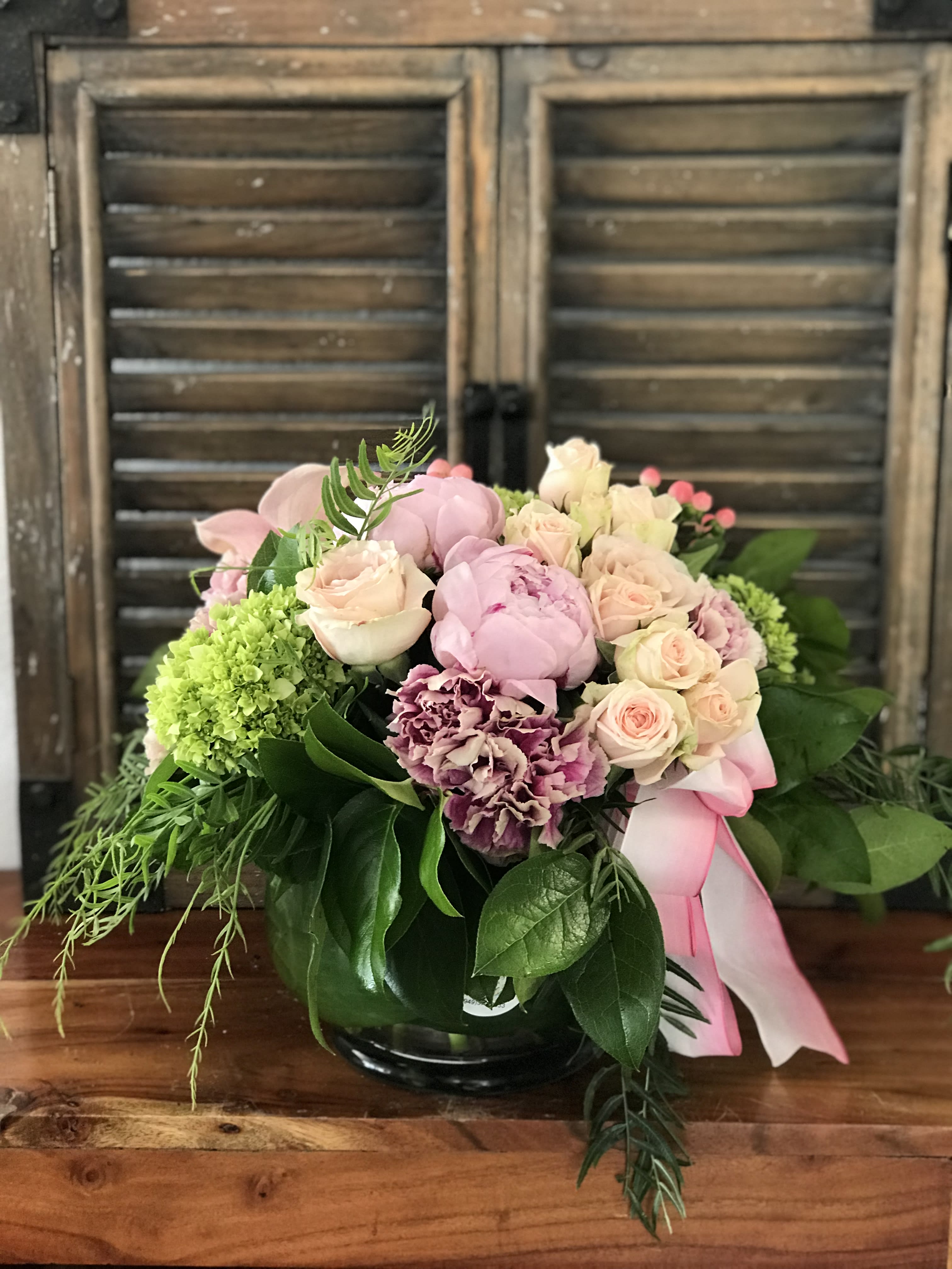 Pink and cream rose bouquet with green hydrangea in a glass vase