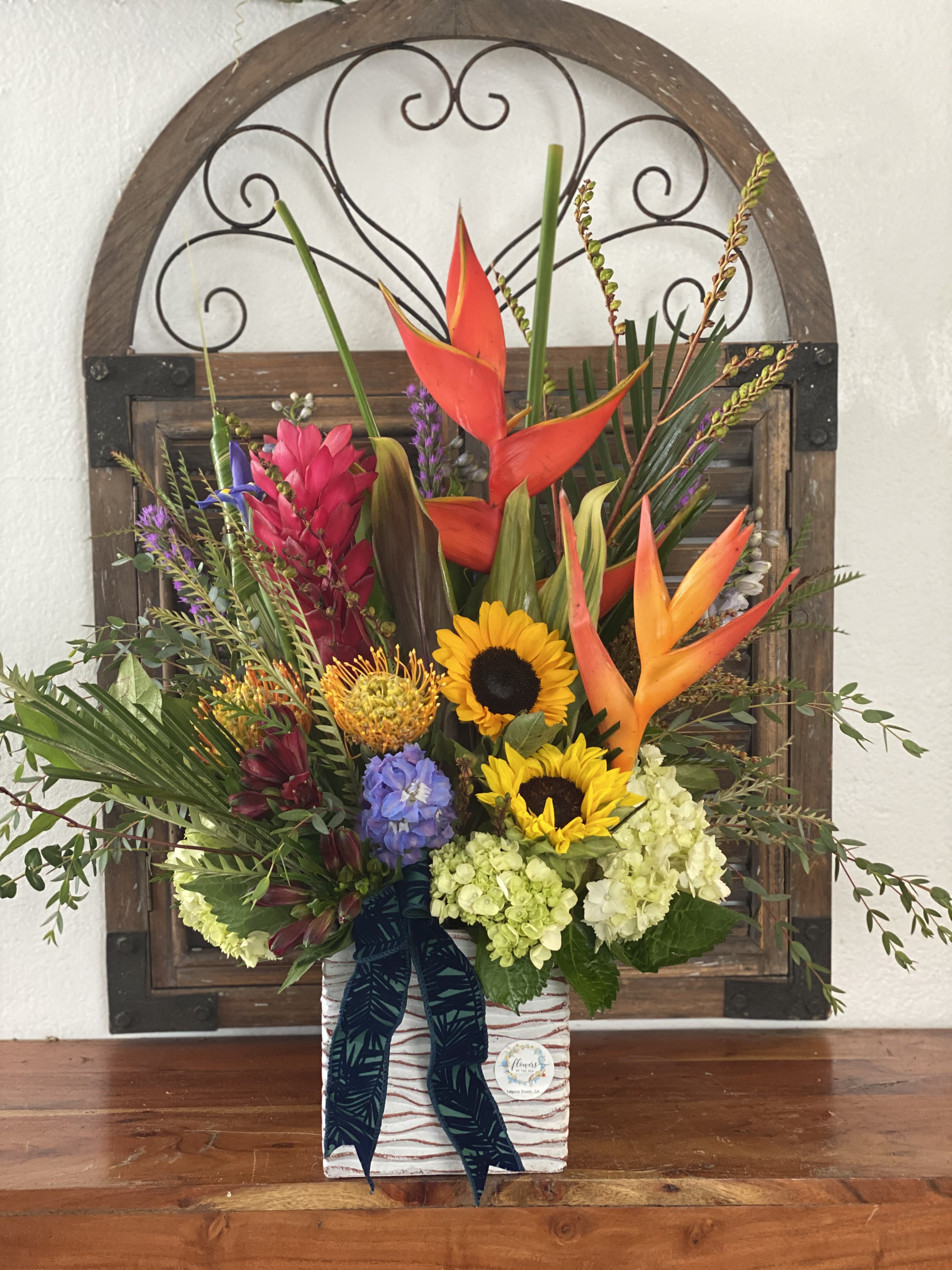 Tropical floral arrangement with sunflowers and orange heliconia in a decorative box