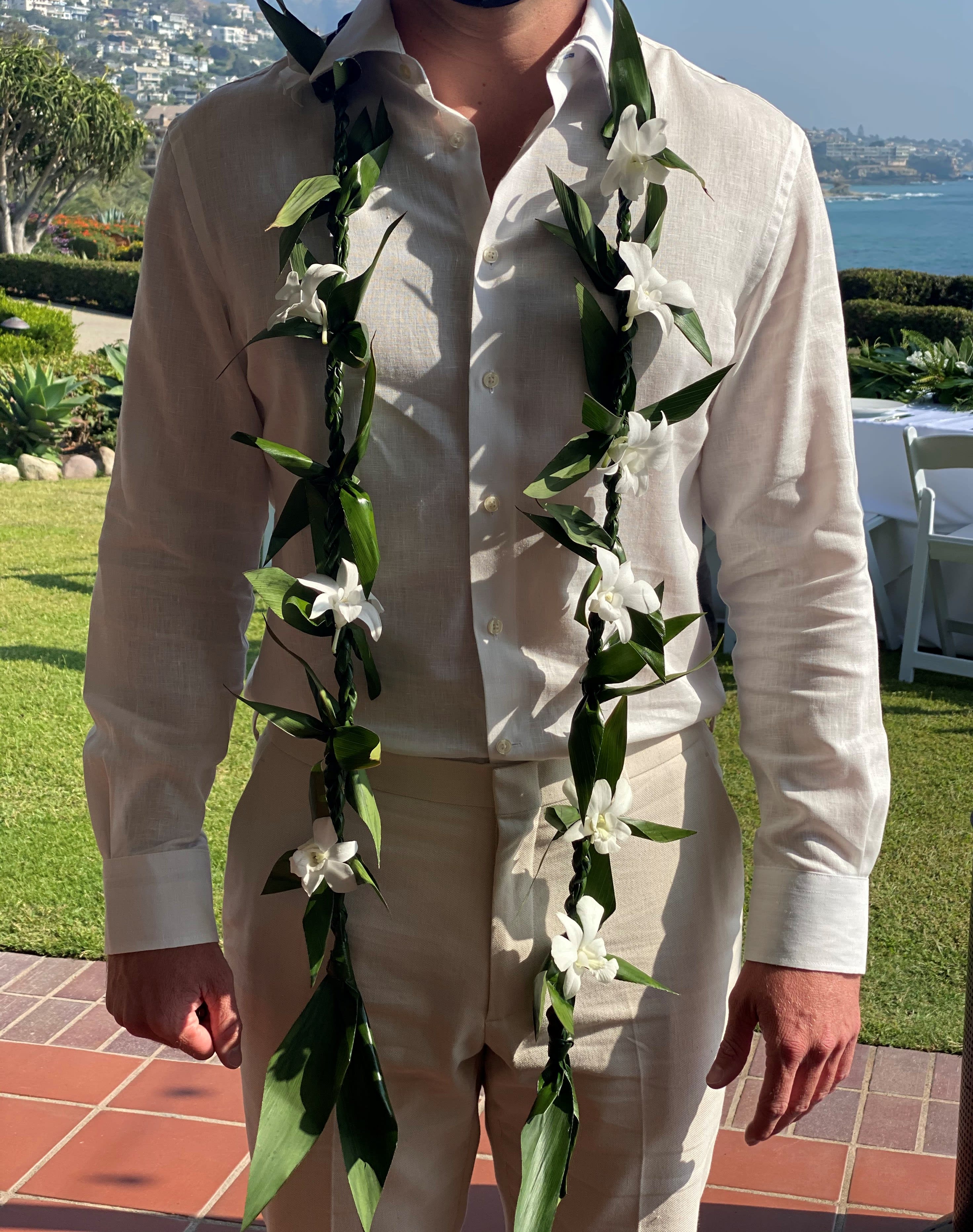 Man wearing a white shirt with two white floral leis