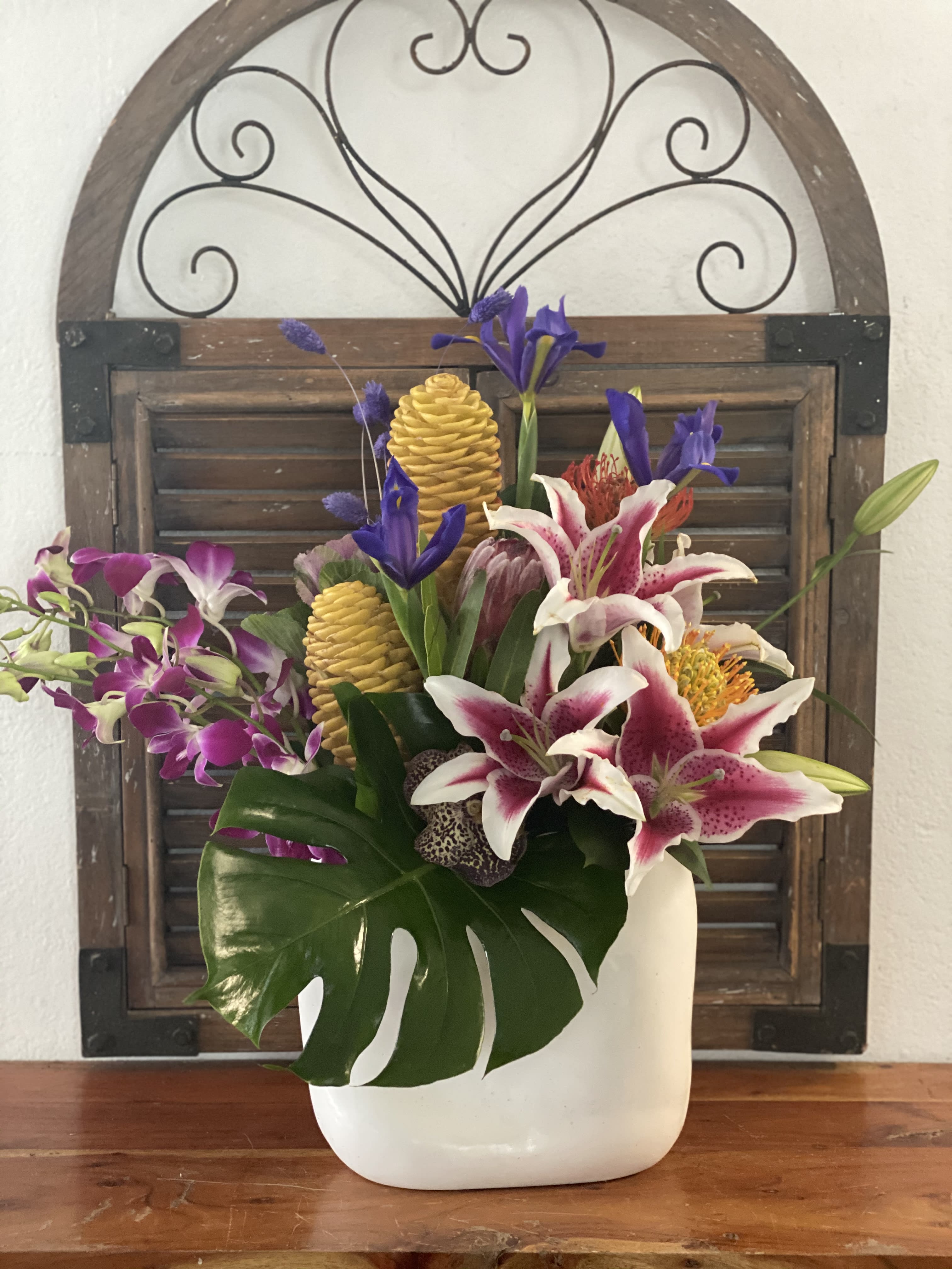 Tropical floral arrangement in a white vase with orchids and lilies