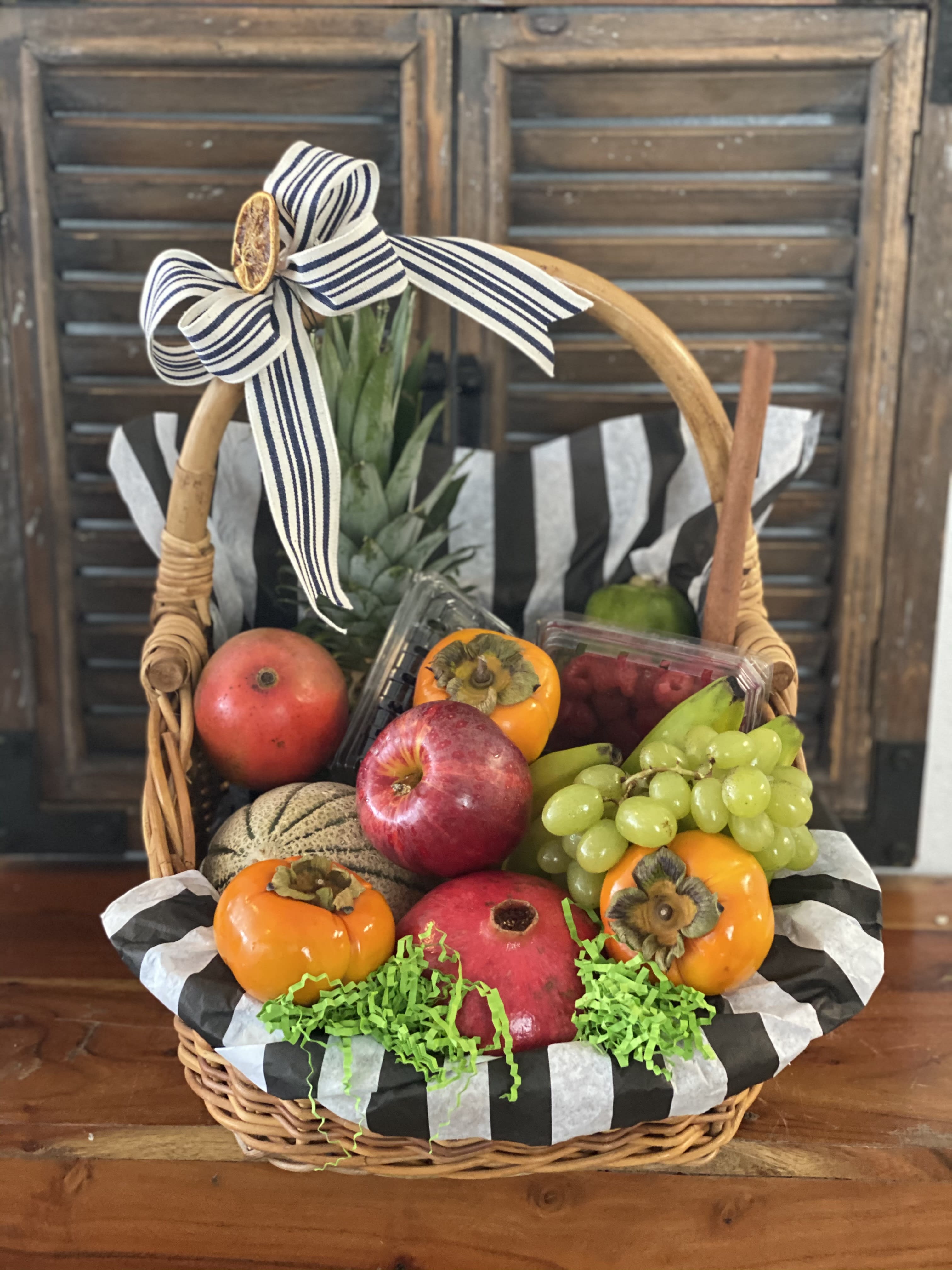 Fruit basket with apples, grapes, persimmons, and a ribbon bow