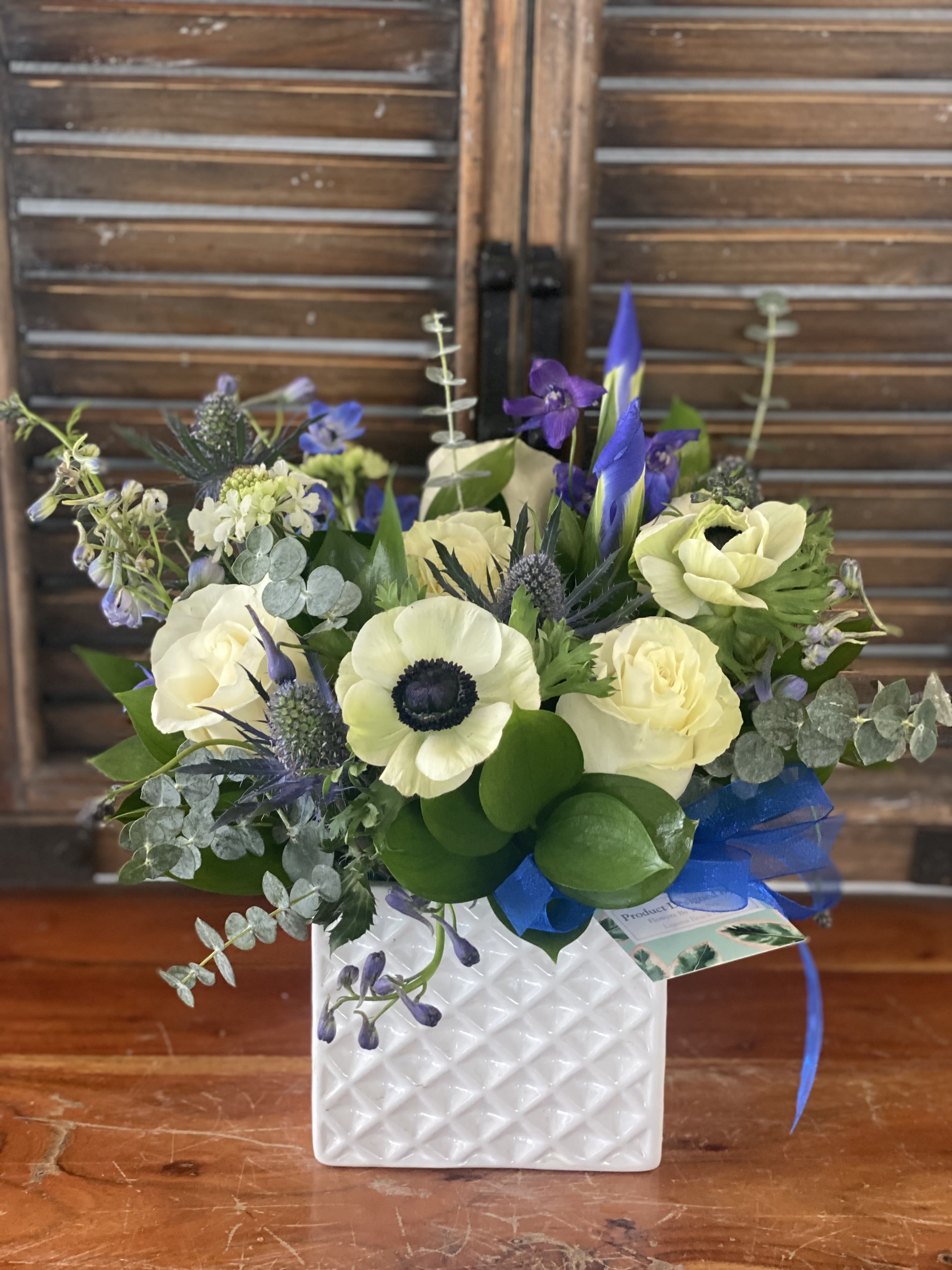 Bouquet of cream and purple flowers in a white textured vase