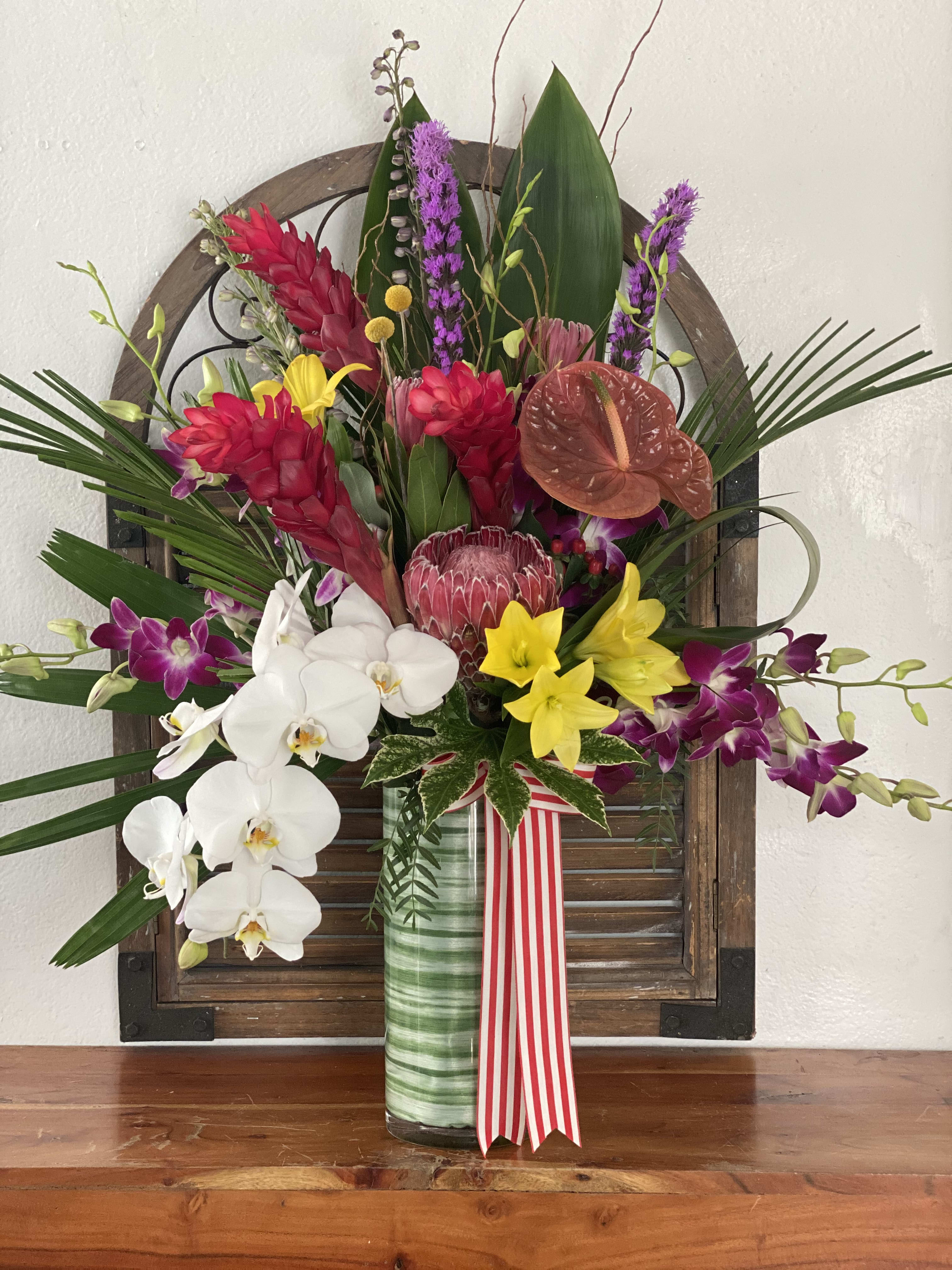 Tropical flower arrangement in a glass vase with orchids and red blooms