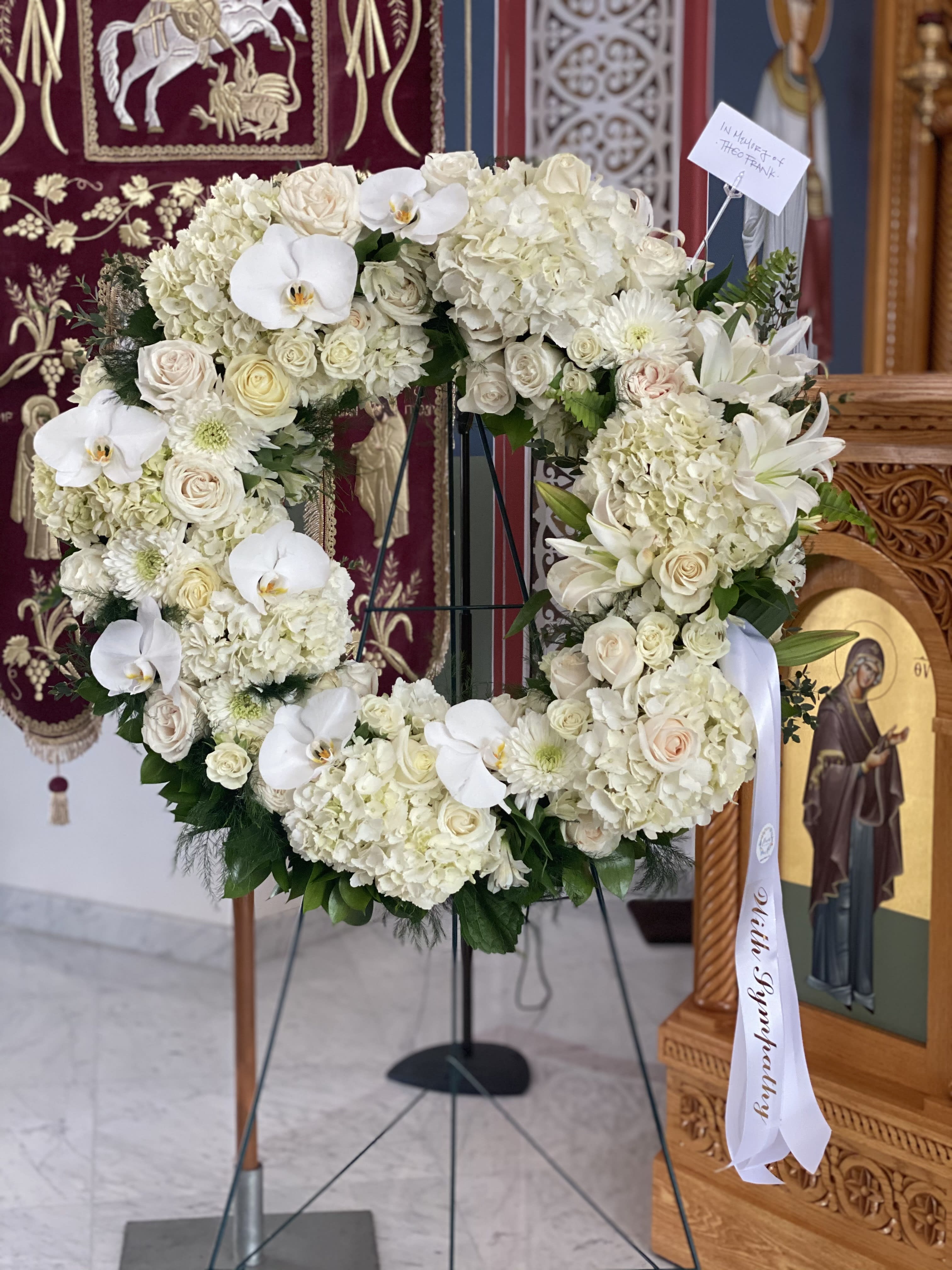 White floral heart wreath on a stand with orchids and roses