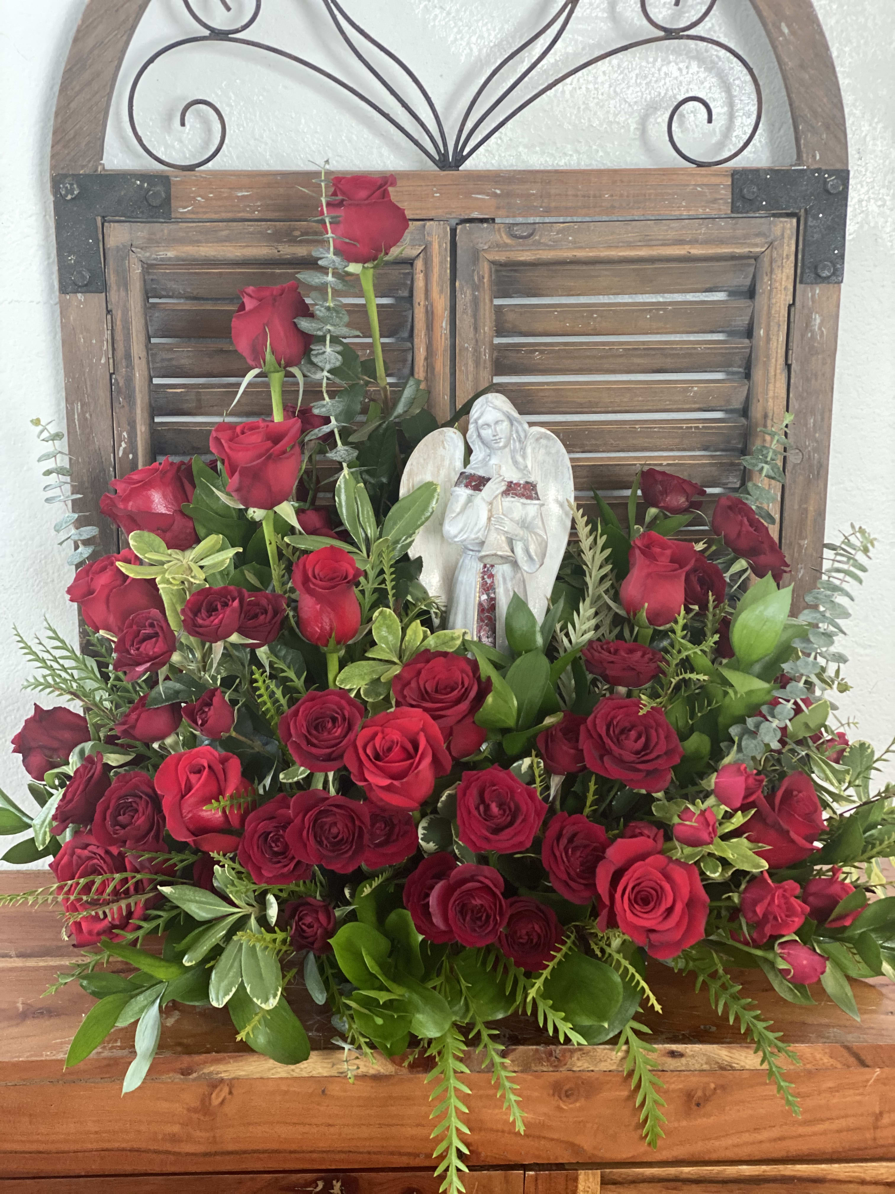 Large arrangement of red roses with an angel figurine