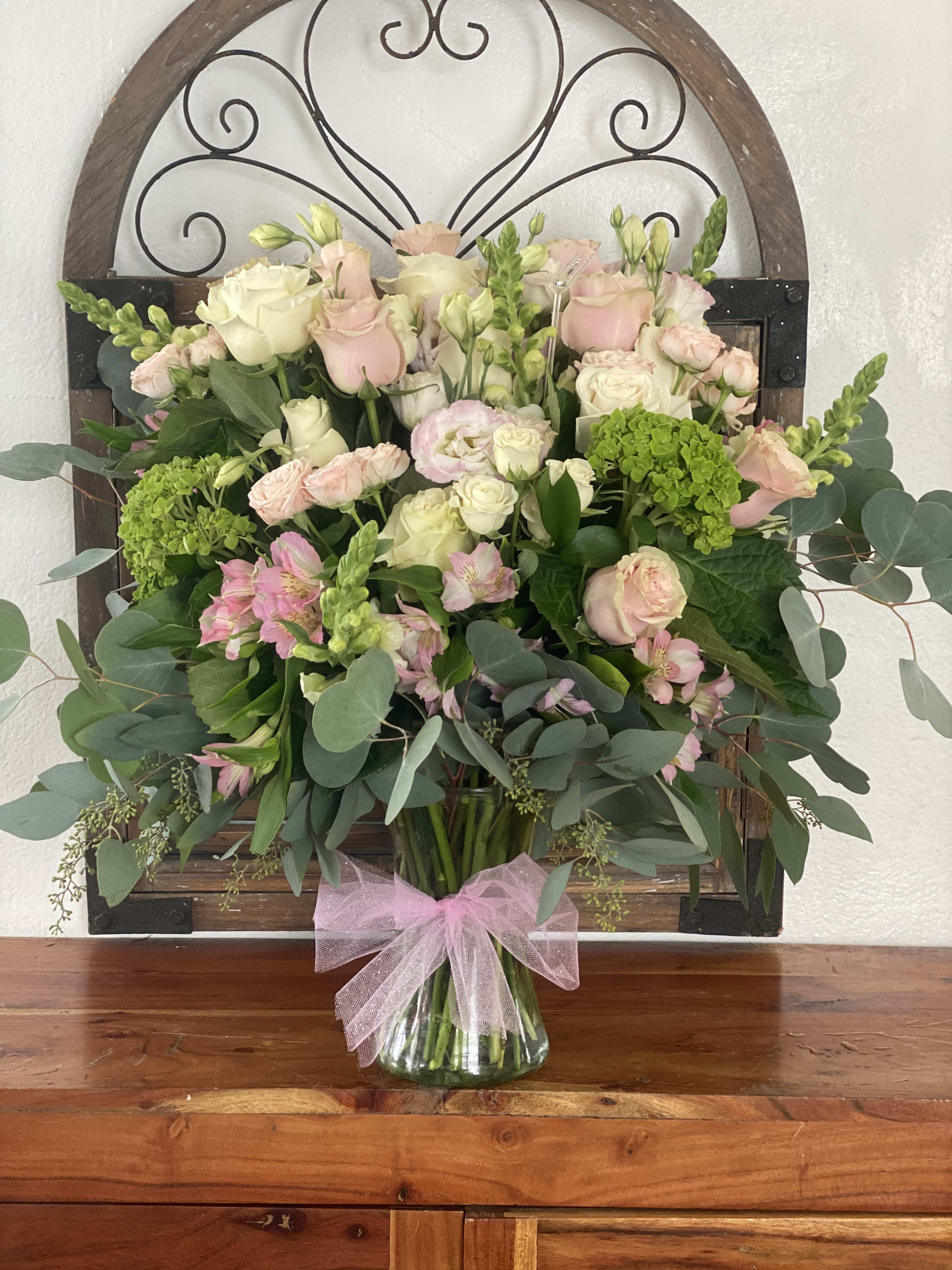 Bouquet of pink and white roses with greenery in a glass vase