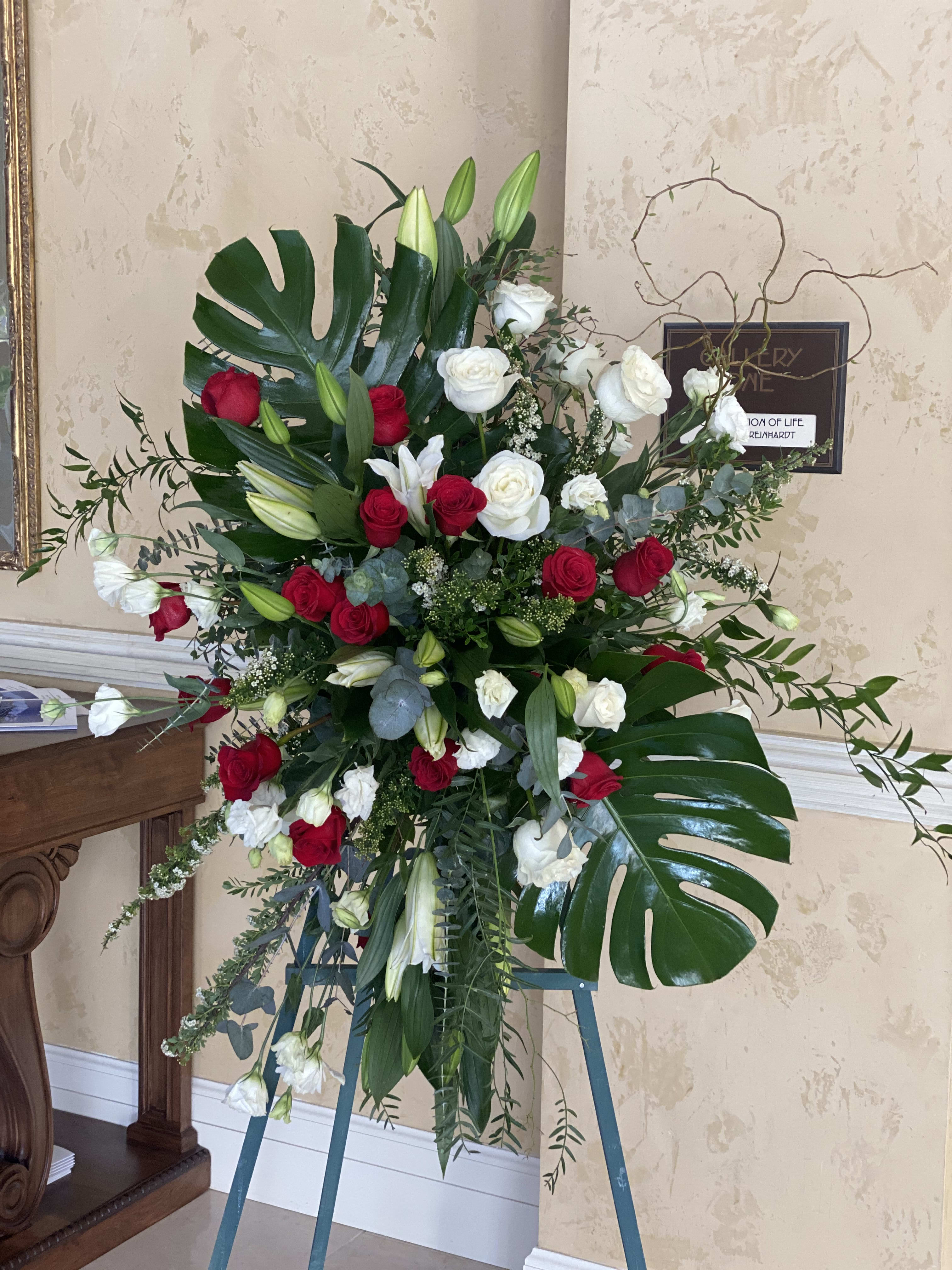 Standing floral spray with red and white roses and lilies on an easel