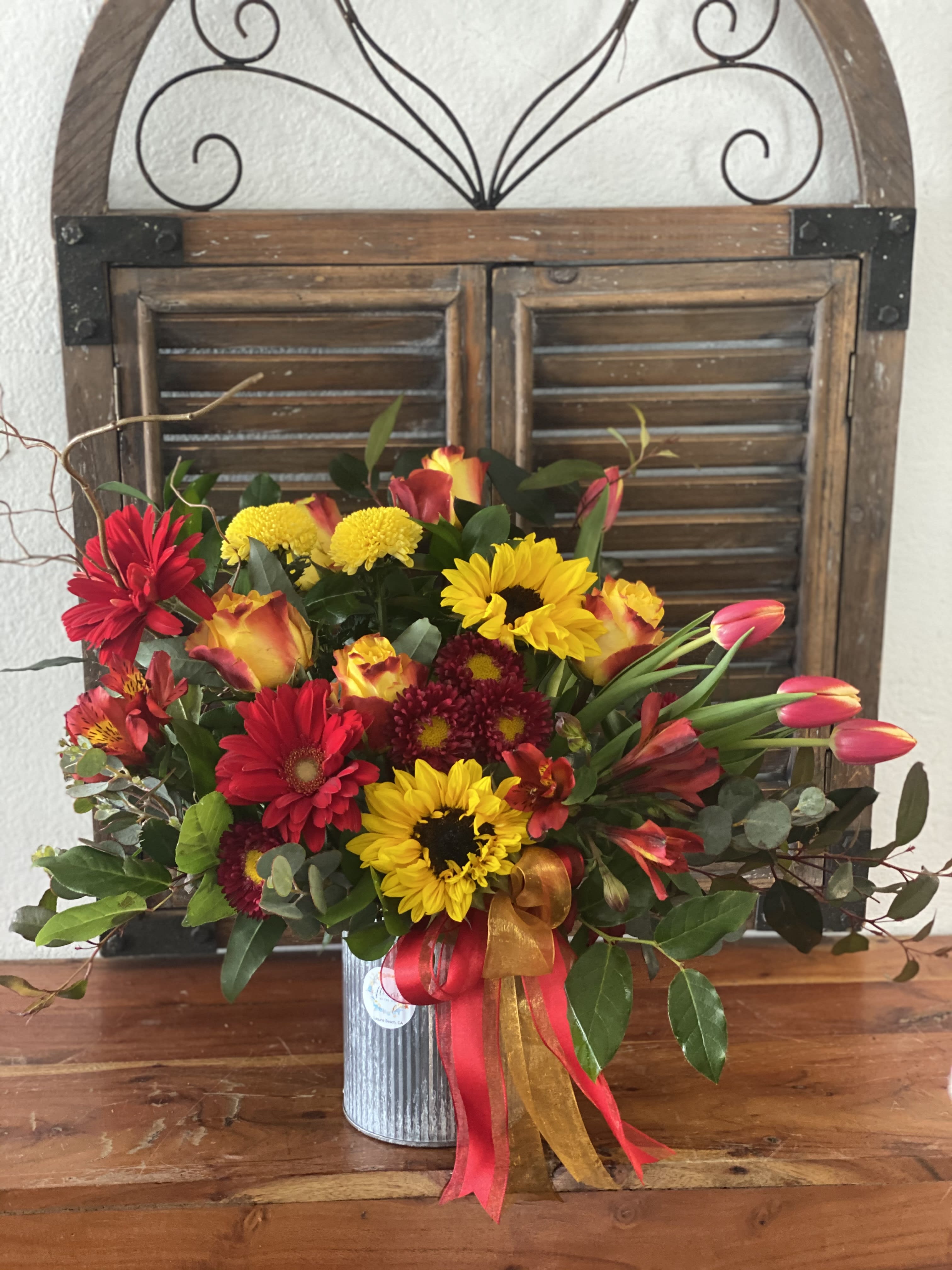 Mixed bouquet of red, yellow, and orange flowers in a metal vase