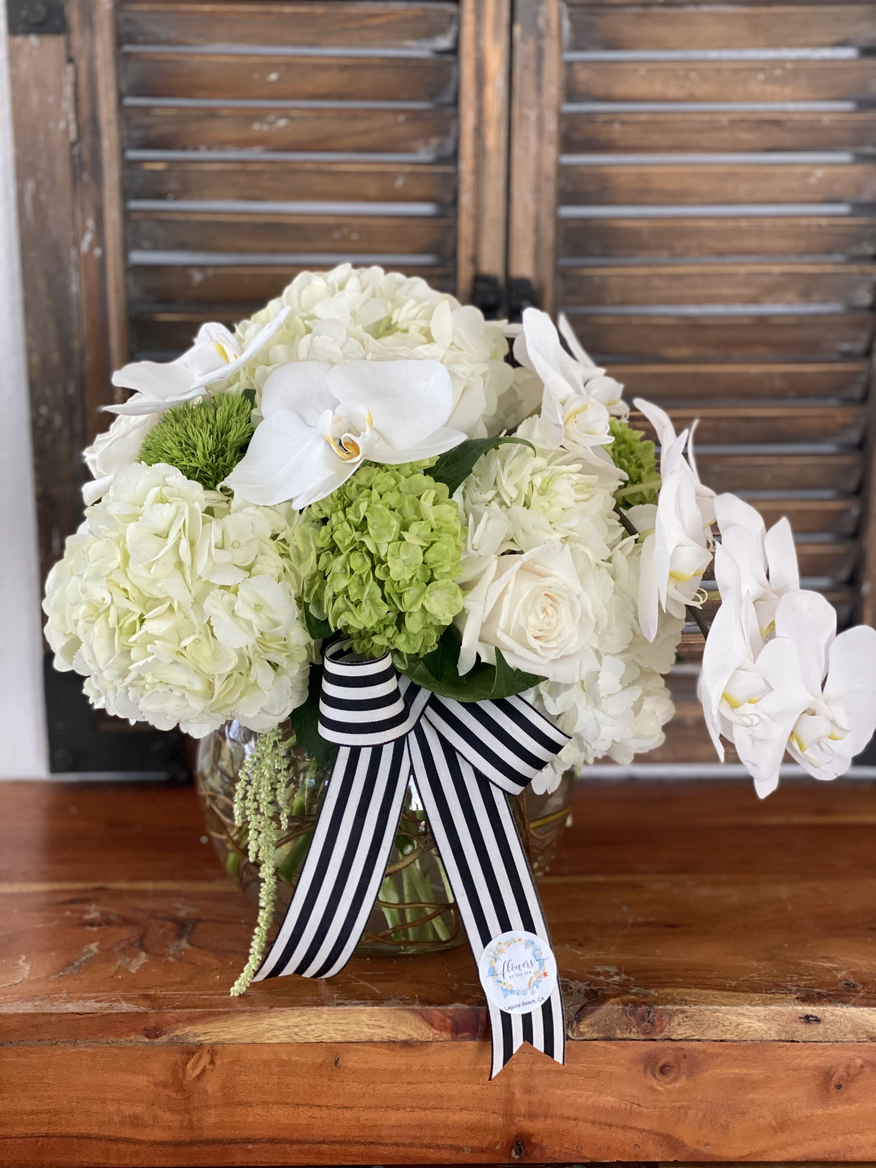 White floral arrangement with orchids and hydrangeas in a glass vase