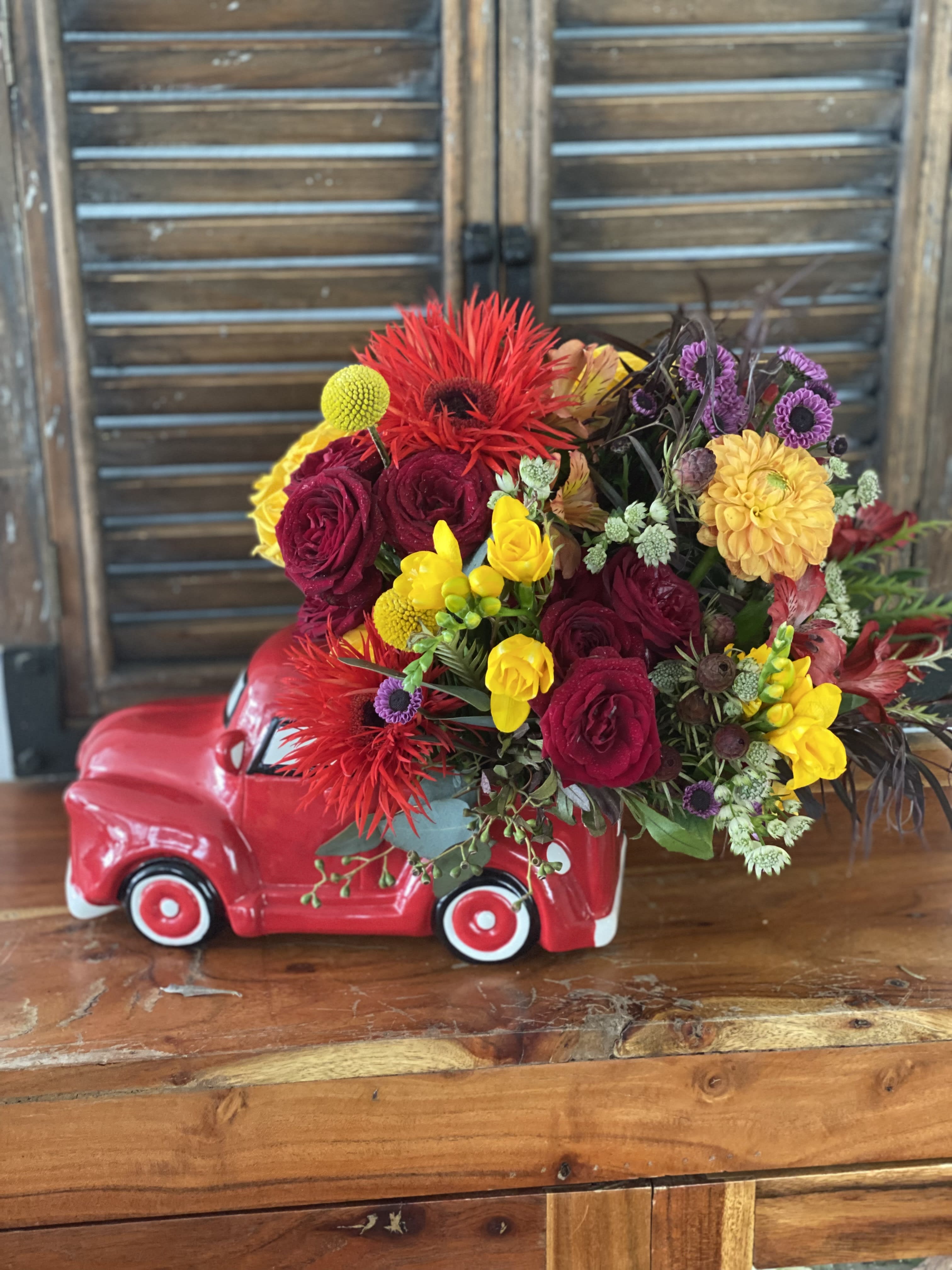 Colorful flower arrangement in a red ceramic truck container